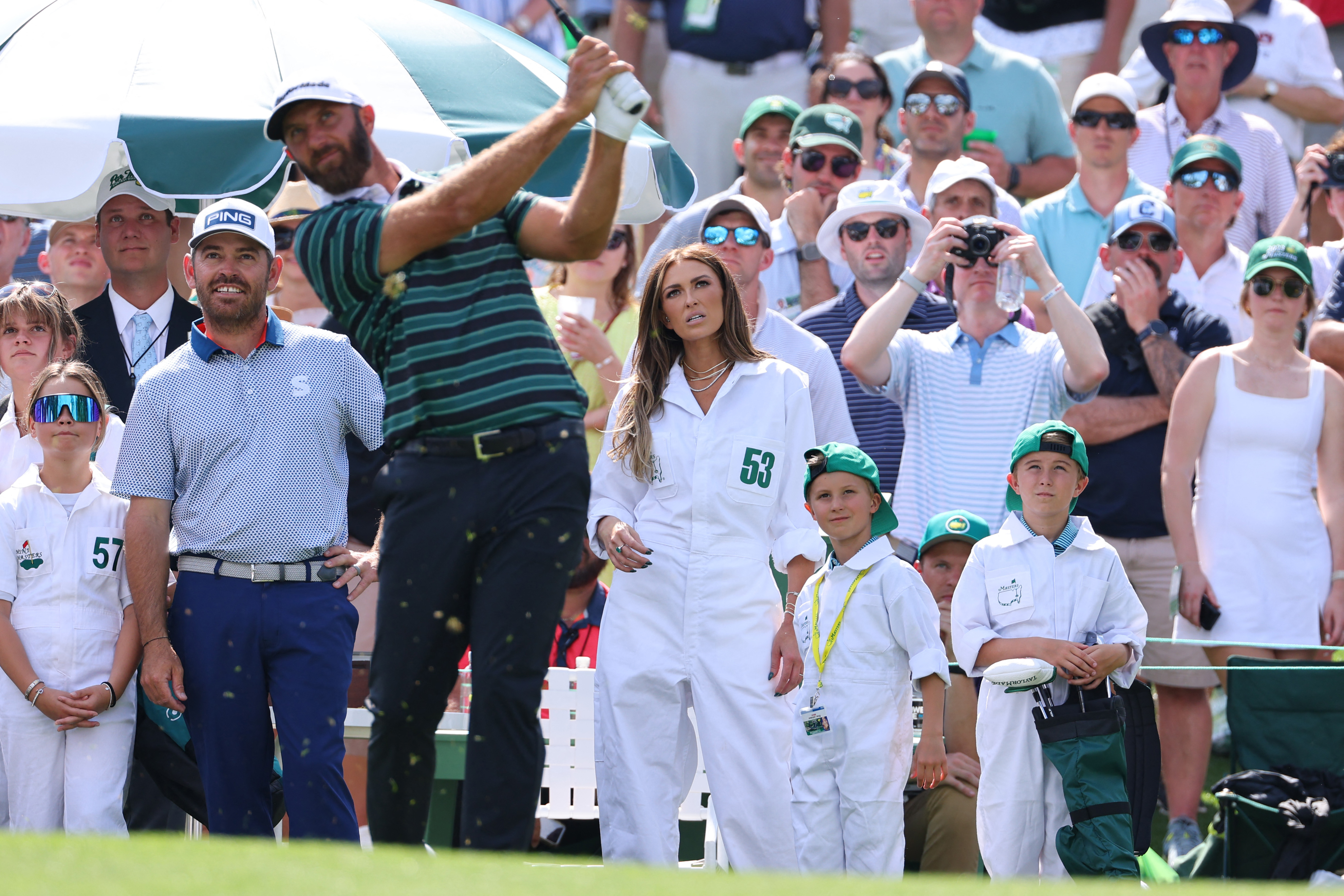 Golf - The Masters - Augusta National Golf Club - Augusta, Georgia, U.S. - April 5, 2023 Dustin Johnson of the U.S. plays his tee shot on the first hole as wife Paulina Gretzky and children Tatum and River look on during the par 3 tournament REUTERS/Mike Blake