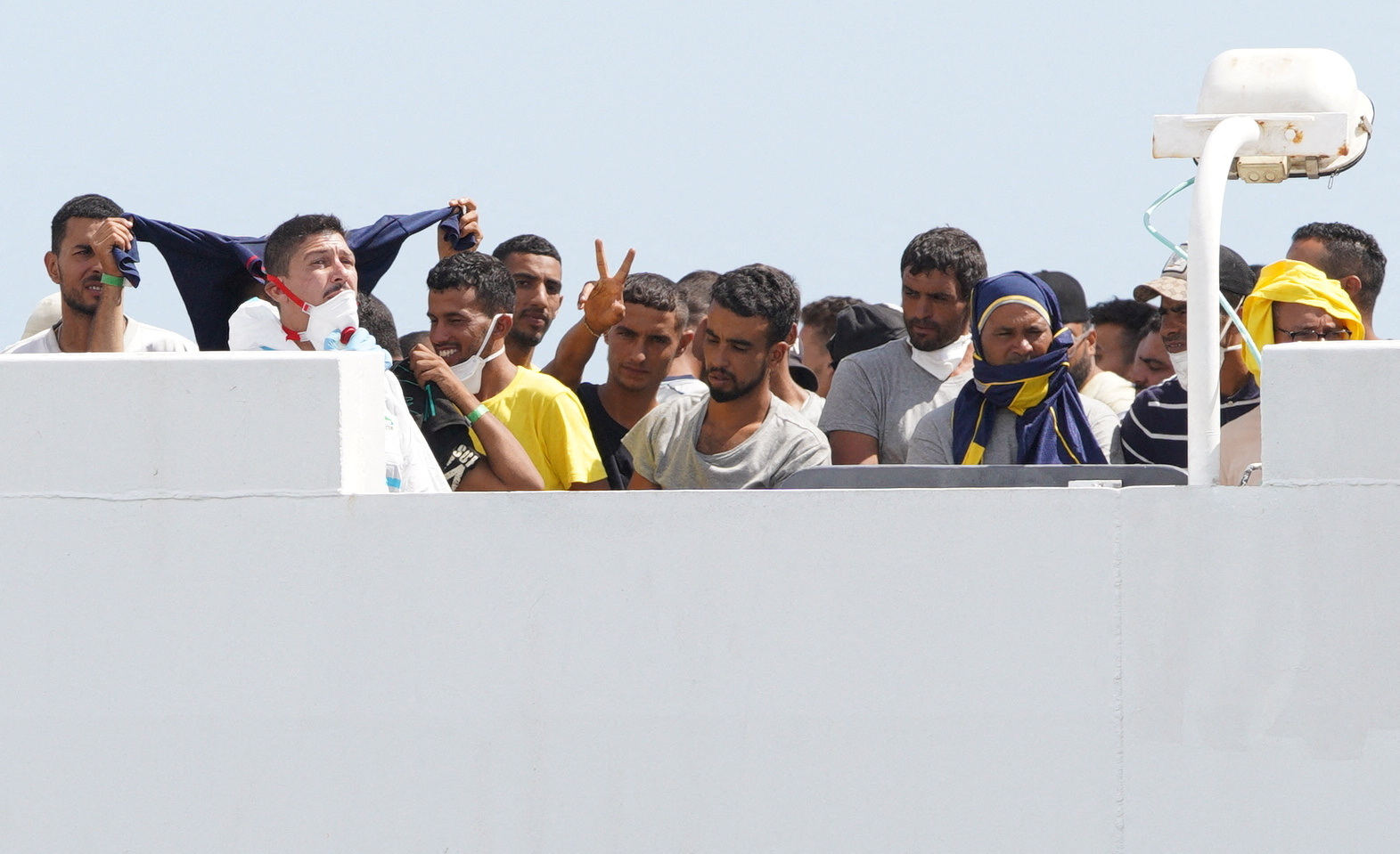 Migrantes gesticulan a bordo de un barco en el que pretenden llegar a países europeos (REUTERS/Antonio Parrinello)