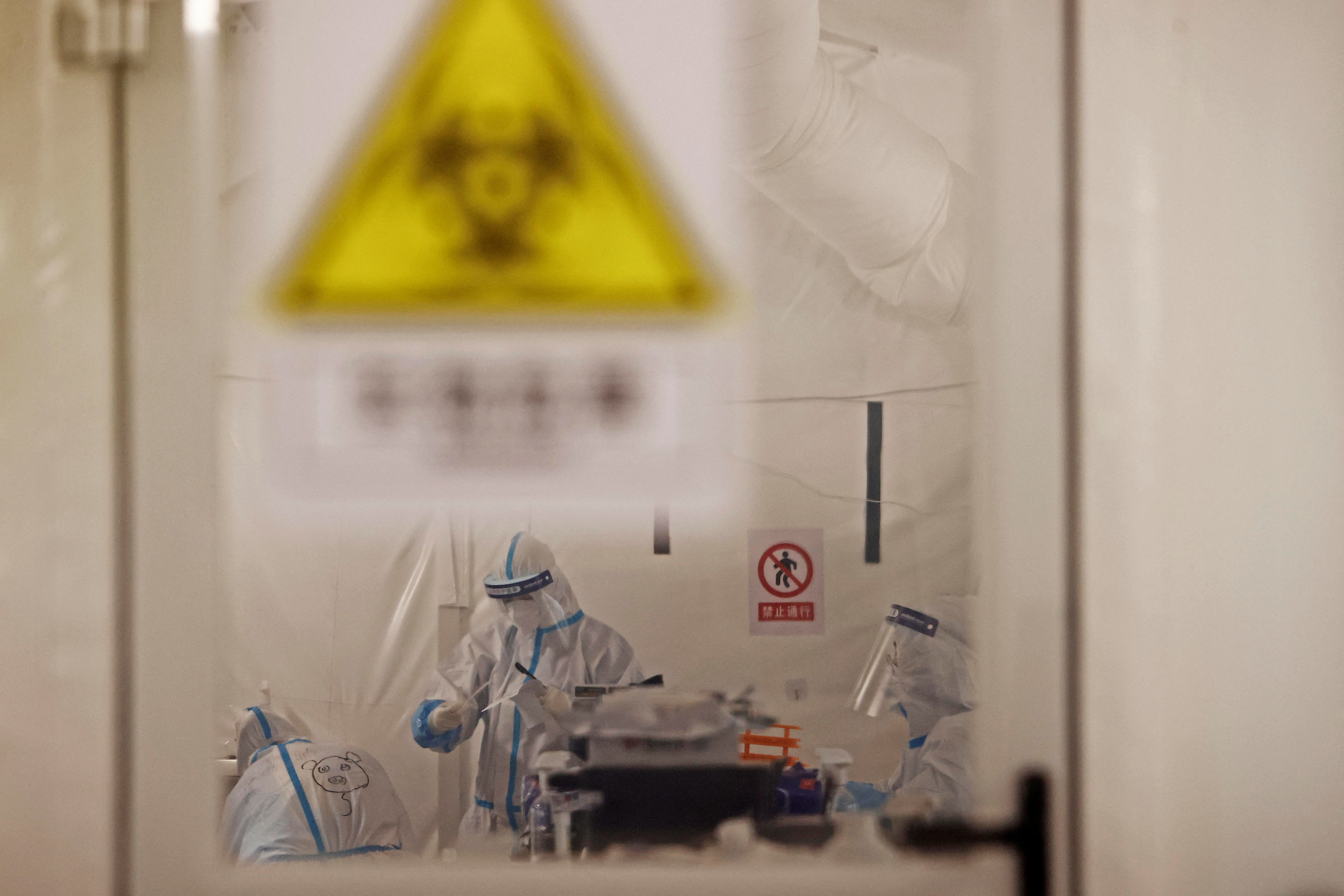 Trabajadores con trajes protectores trabajan dentro de un laboratorio de pruebas de ácido nucleico improvisado, luego del brote de la enfermedad por coronavirus (COVID-19) en Shanghái, China. cnsphoto vía REUTERS
