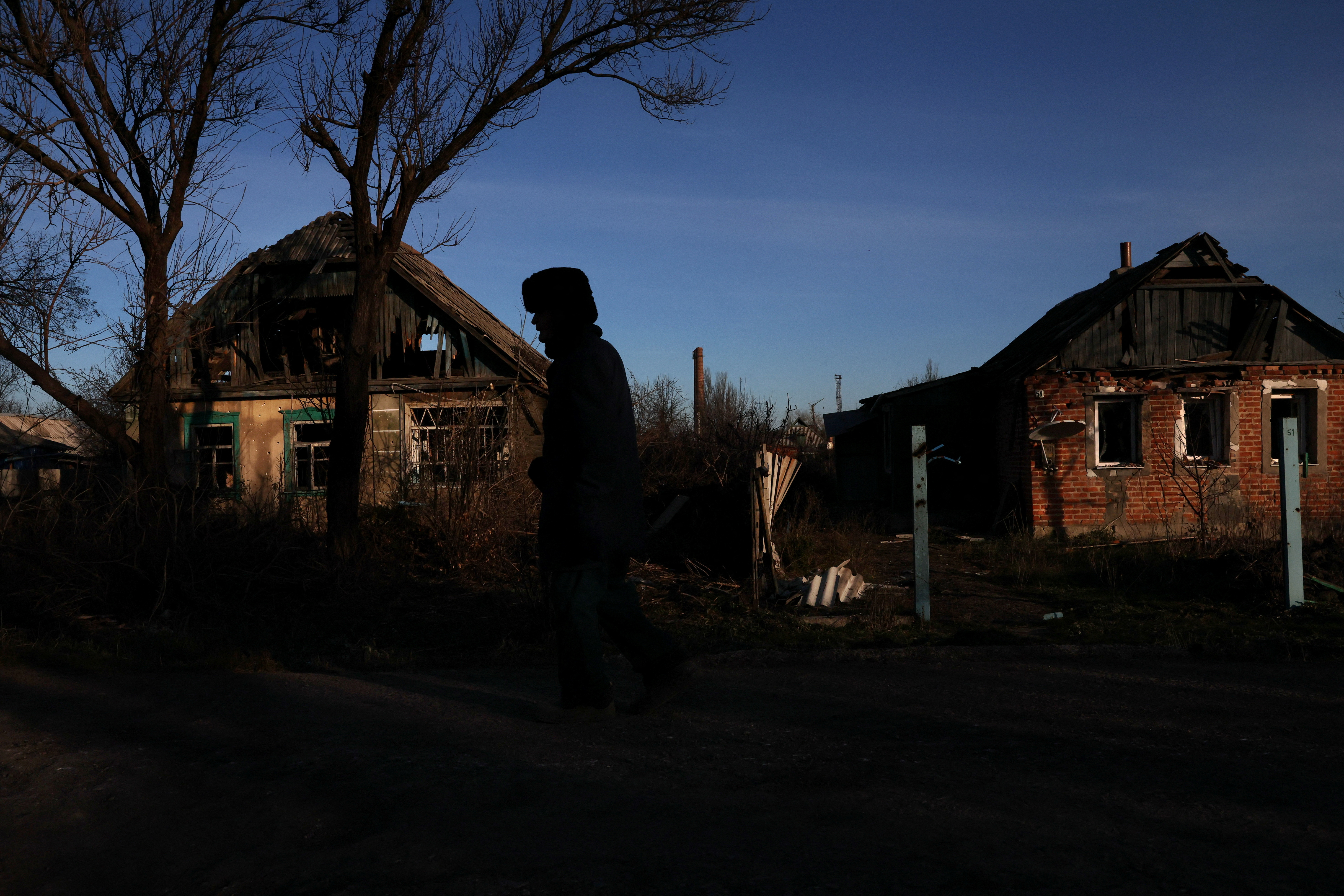 Un hombre camina, a oscuras, por una calle de casas destruidas mientras continúa la invasión rusa sobre Ucrania en Siversk (REUTERS/ Leah Millis)