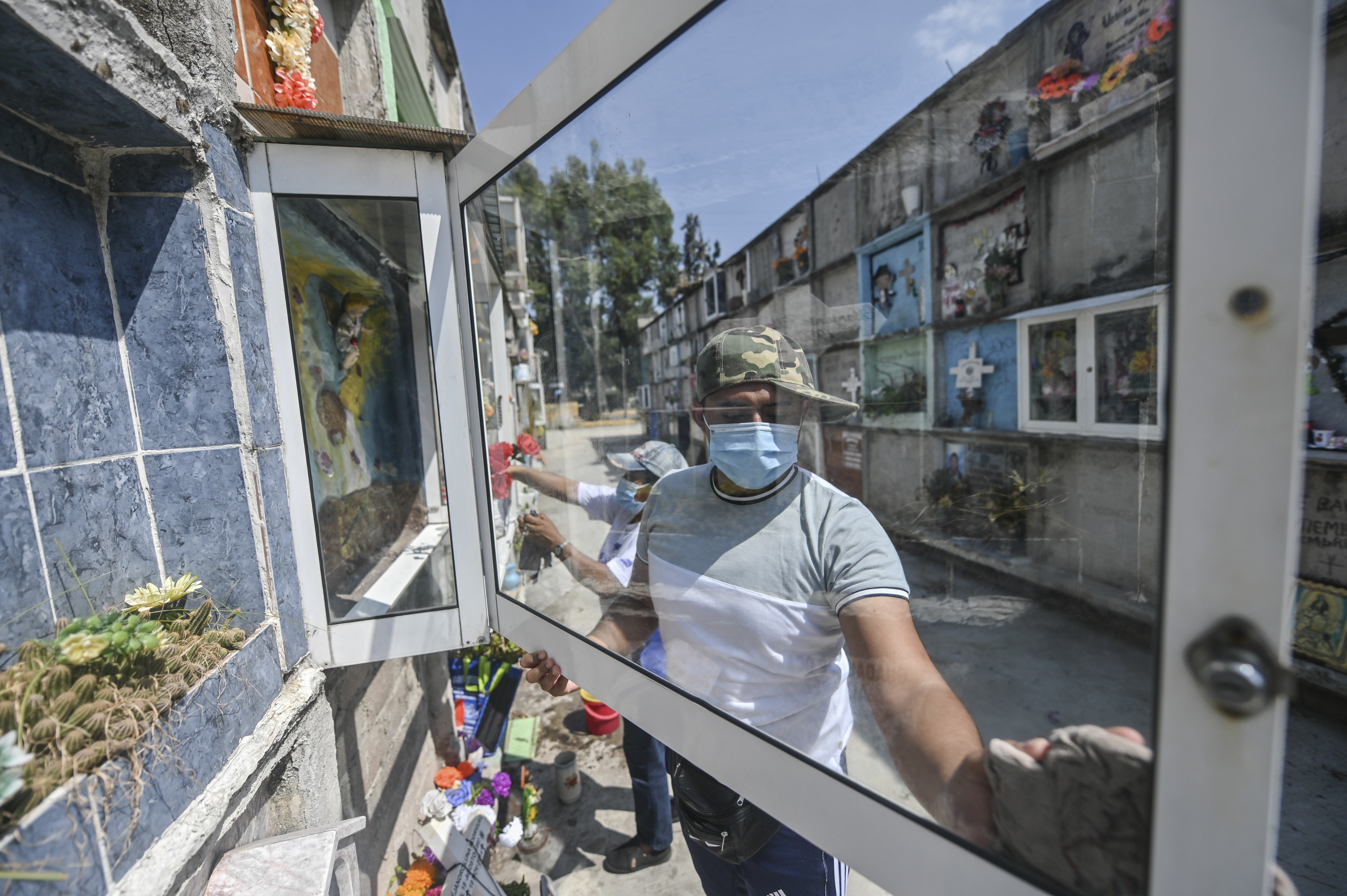 Personas decoran la tumba de un familiar antes del Día de Muertos en el panteón municipal de Nezahualcóyotl, México, el 28 de octubre de 2020, en medio de la pandemia del coronavirus COVID-19.