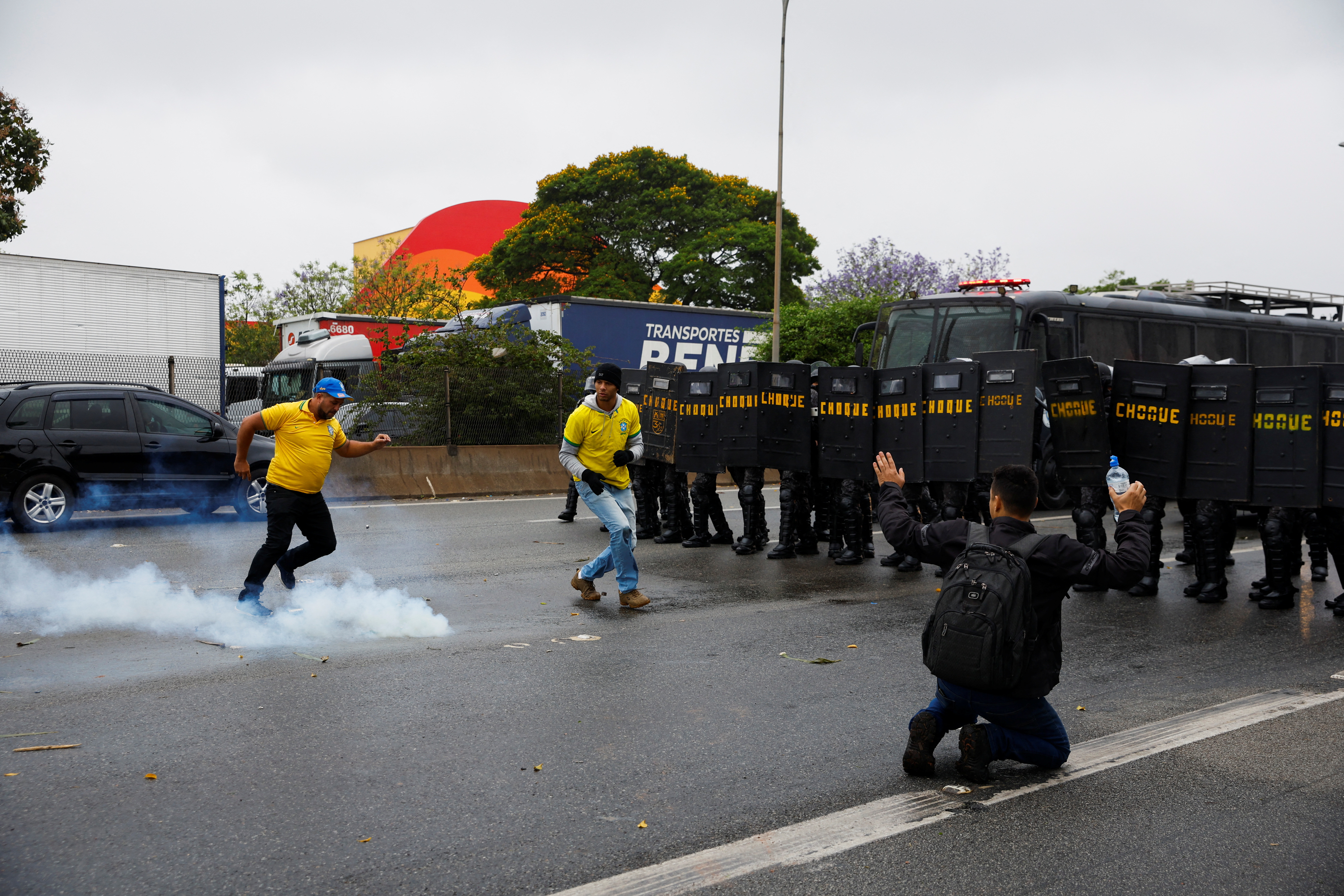 Los miembros de la policía antidisturbios se colocan en posición mientras un simpatizante del presidente de Brasil, Jair Bolsonaro, intenta patear una botella de gas.