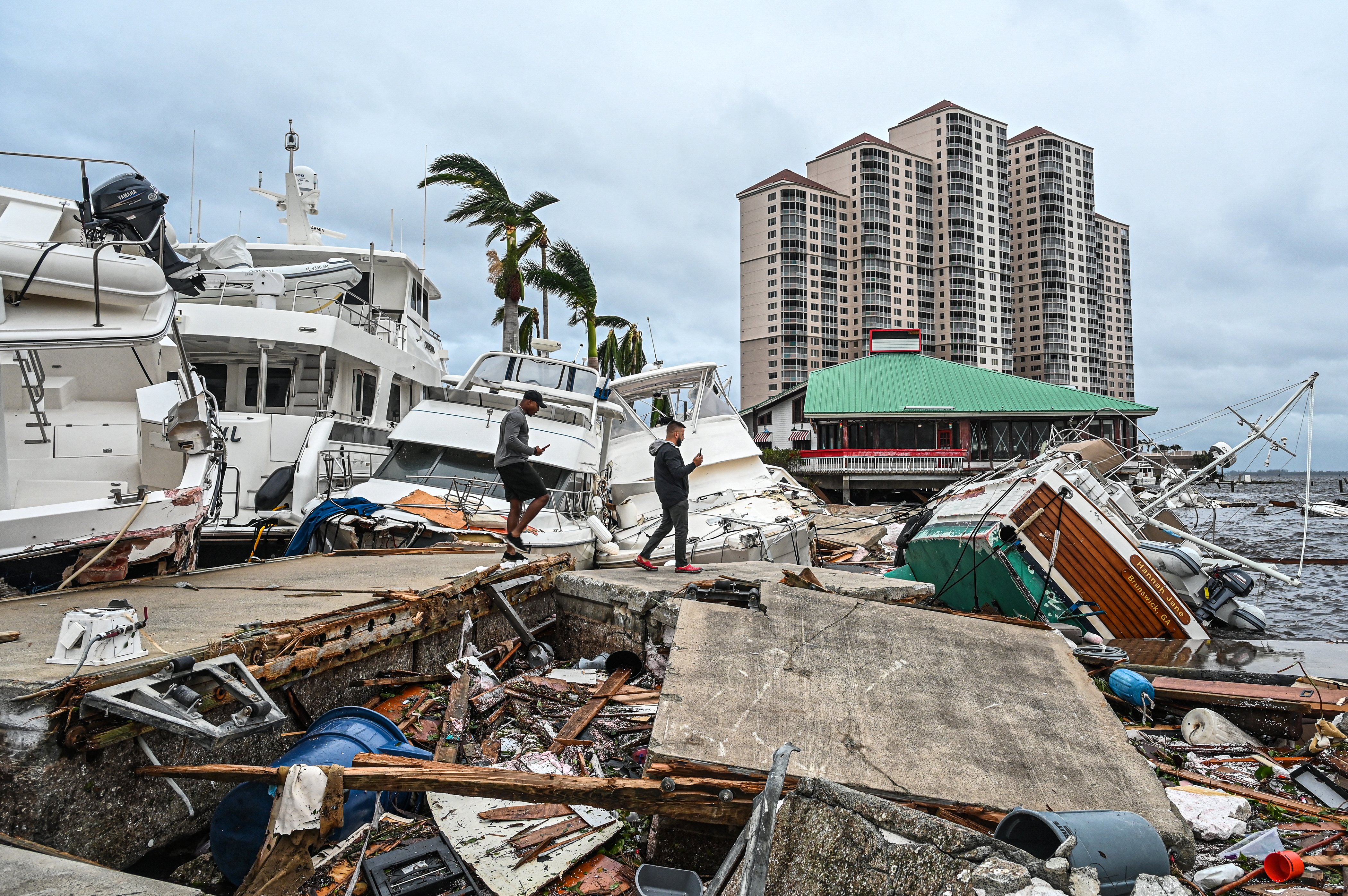 Los residentes inspeccionan los daños a un puerto deportivo mientras los barcos están parcialmente sumergidos tras el paso del huracán Ian en Fort Myers, Florida, el 29 de septiembre de 2022. (Giorgio VIERA / AFP)