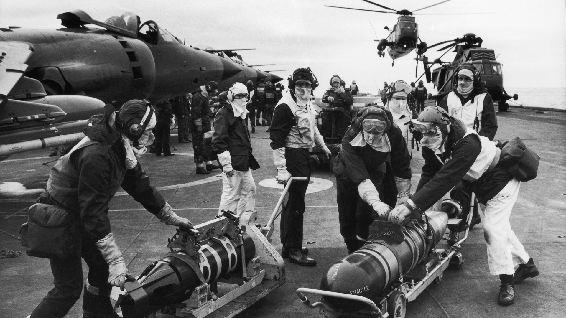 Personal de armas mueve torpedos en la cubierta del HMS Hermes durante el conflicto de las Malvinas, mayo de 1982. Los torpedos son para rearmar los helicópteros Sea King para contrarrestar la amenaza de los submarinos argentinos (Martin Cleaver/Pool/Getty Images)