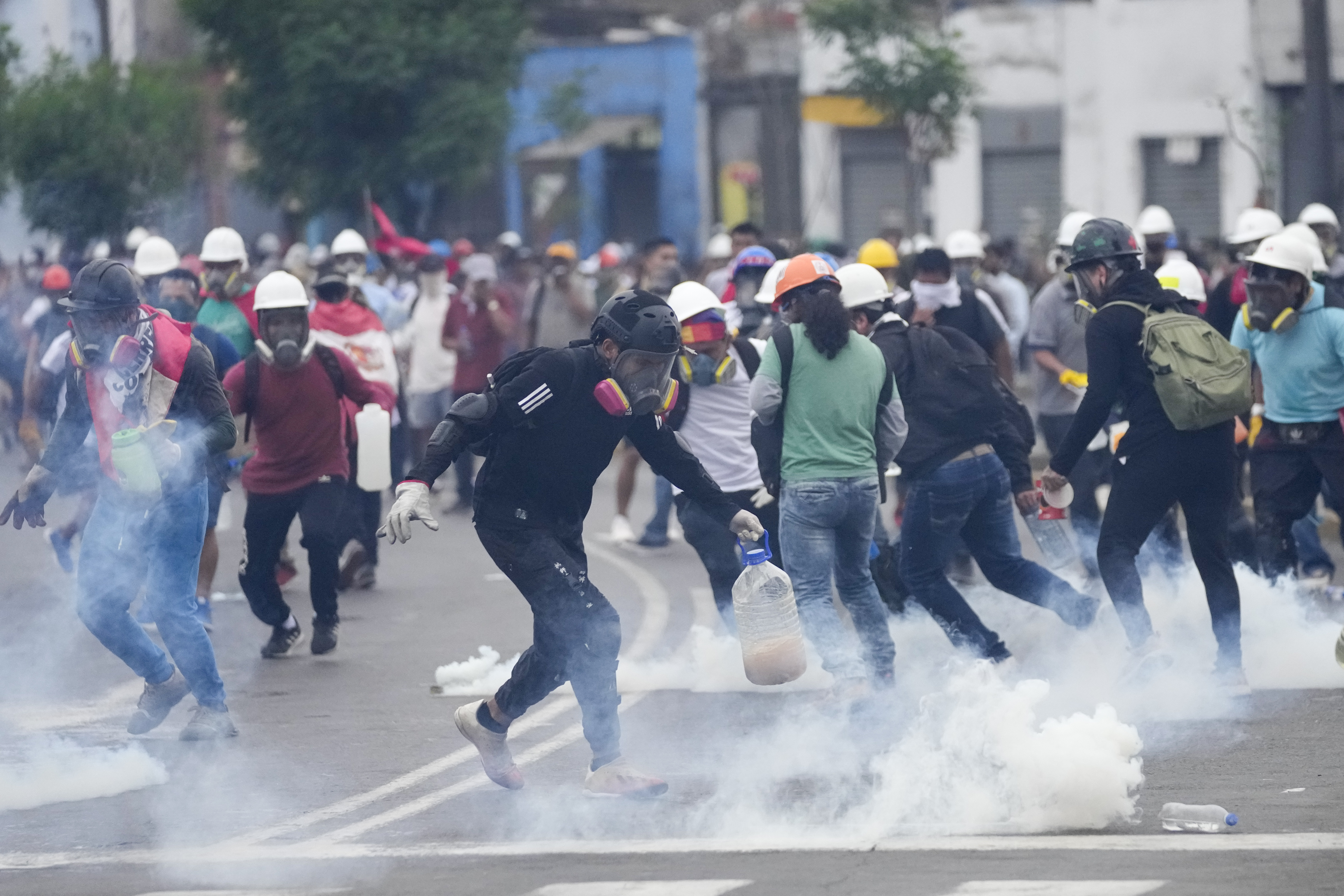 Several anti-government protesters collect tear gas canisters fired at them by the police to dissolve them in Lima, Peru, on Saturday, January 28, 2023. The protesters demand the resignation of President Dina Boluarte and legislators, the advancement of elections, the call to a constituent assembly, justice for those killed in the protests and the freedom of the ousted president Pedro Castillo.  (AP Photo/Guadalupe Pardo)