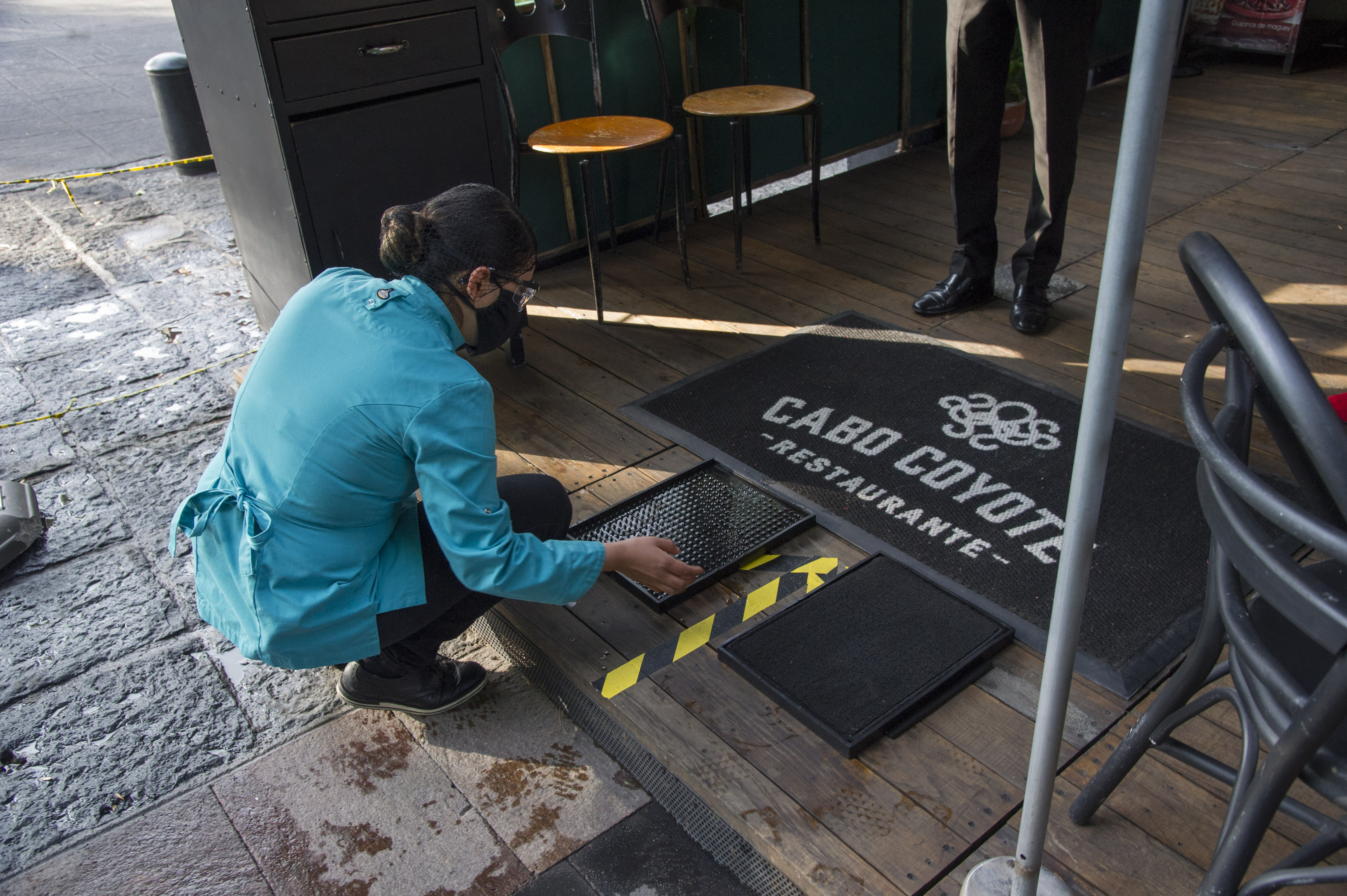 Un trabajador del restaurante Cabo Coyote arregla una estera para desinfectar los zapatos de los clientes en el barrio de Coyoacán, Ciudad de México, el 1 de julio de 2020 durante la pandemia COVID-19. (Foto: CLAUDIO CRUZ / AFP)