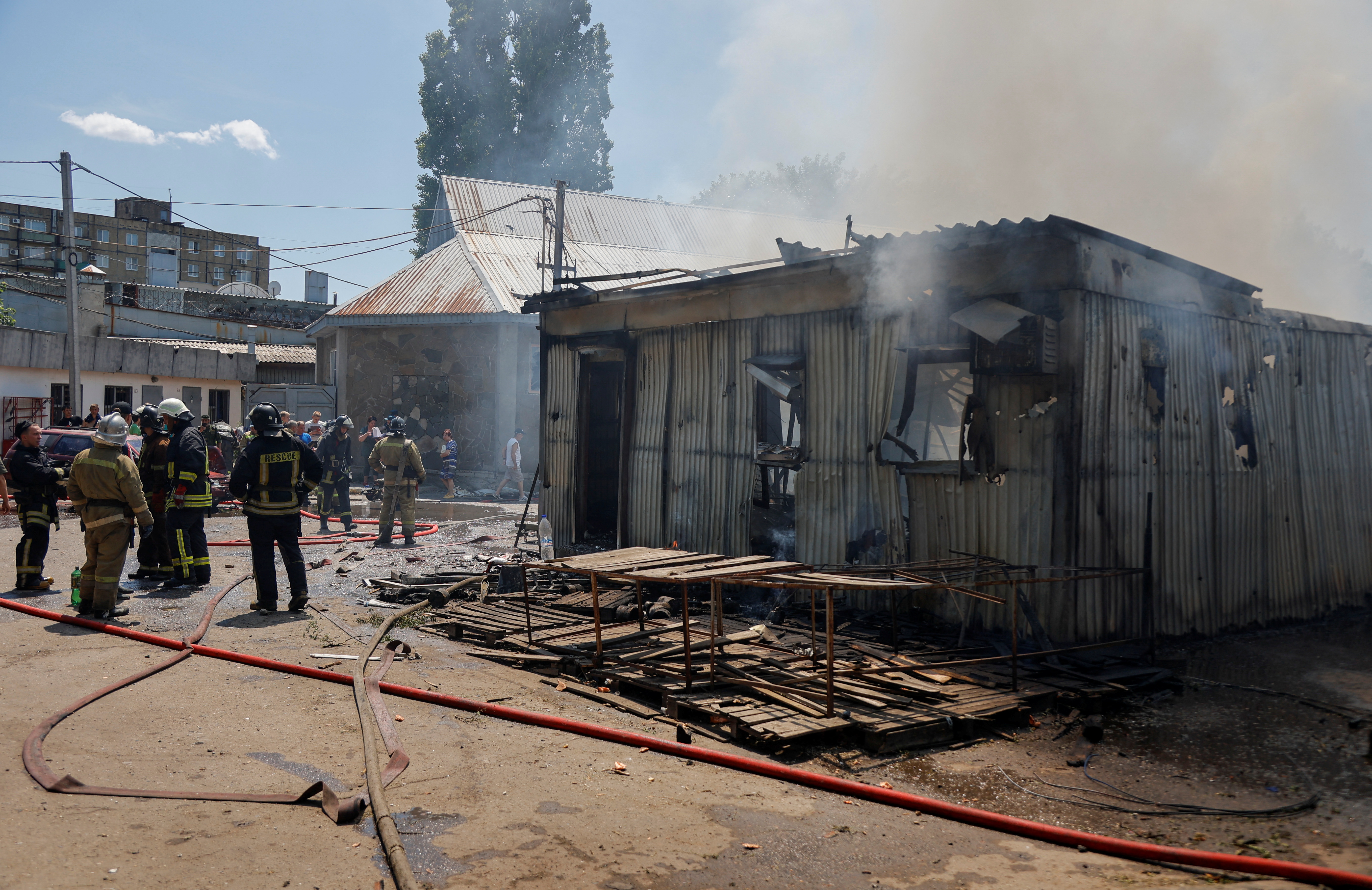 Los bomberos se reúnen cerca de un edificio destruido en el mercado central de Maisky (REUTERS)
