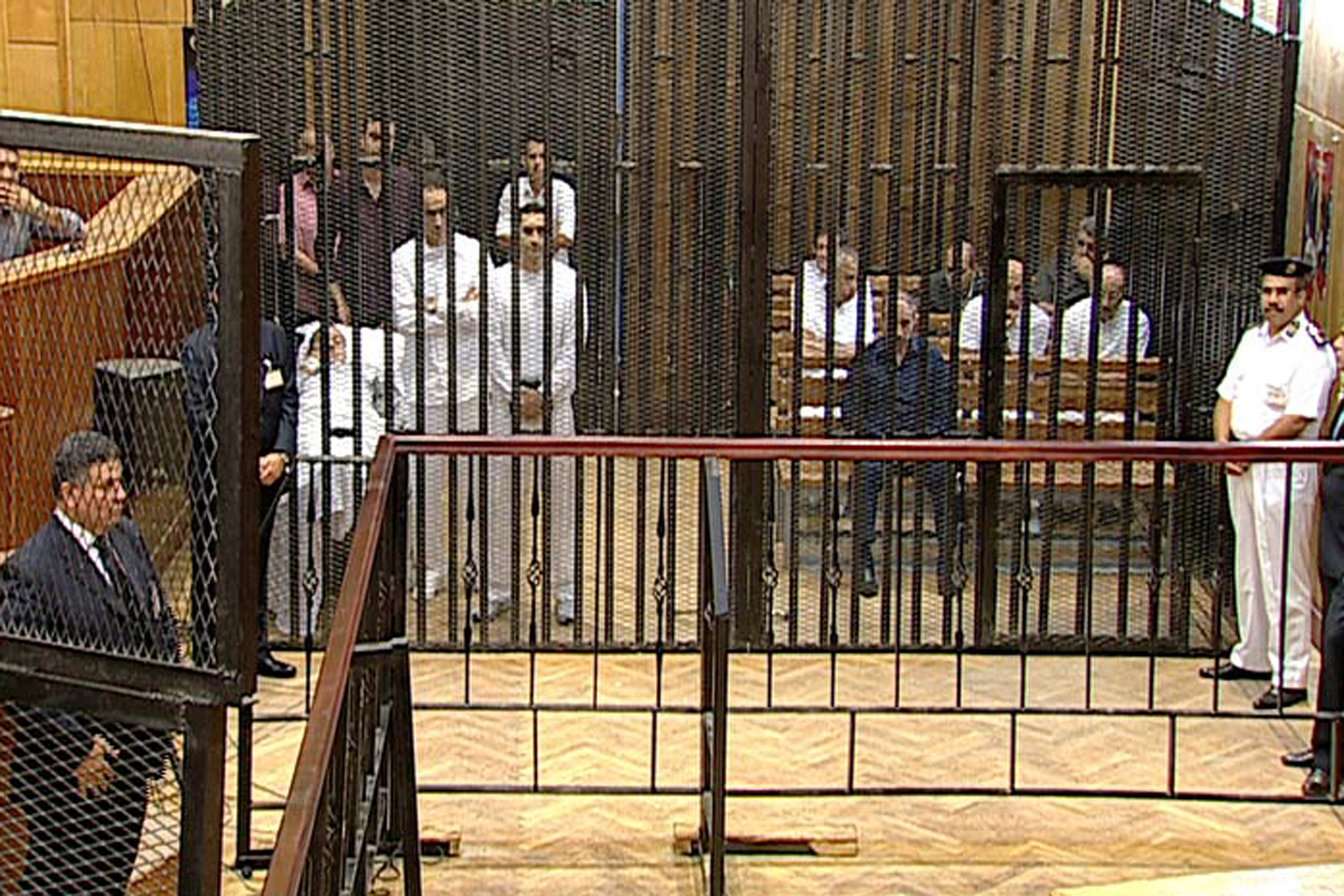 Los acusados, entre ellos el ex presidente egipcio Hosni Mubarak (en la cama, 2º izq.), sus dos hijos Gamal (de pie, con los brazos cruzados) y Alaa Mubarak, y el ex ministro del Interior Habib al-Adli (sentado en primera fila, de negro) asisten a su juicio en la Academia de Policía de El Cairo, Egipto, 3 de agosto de 2011 (REUTERS/Stringer)