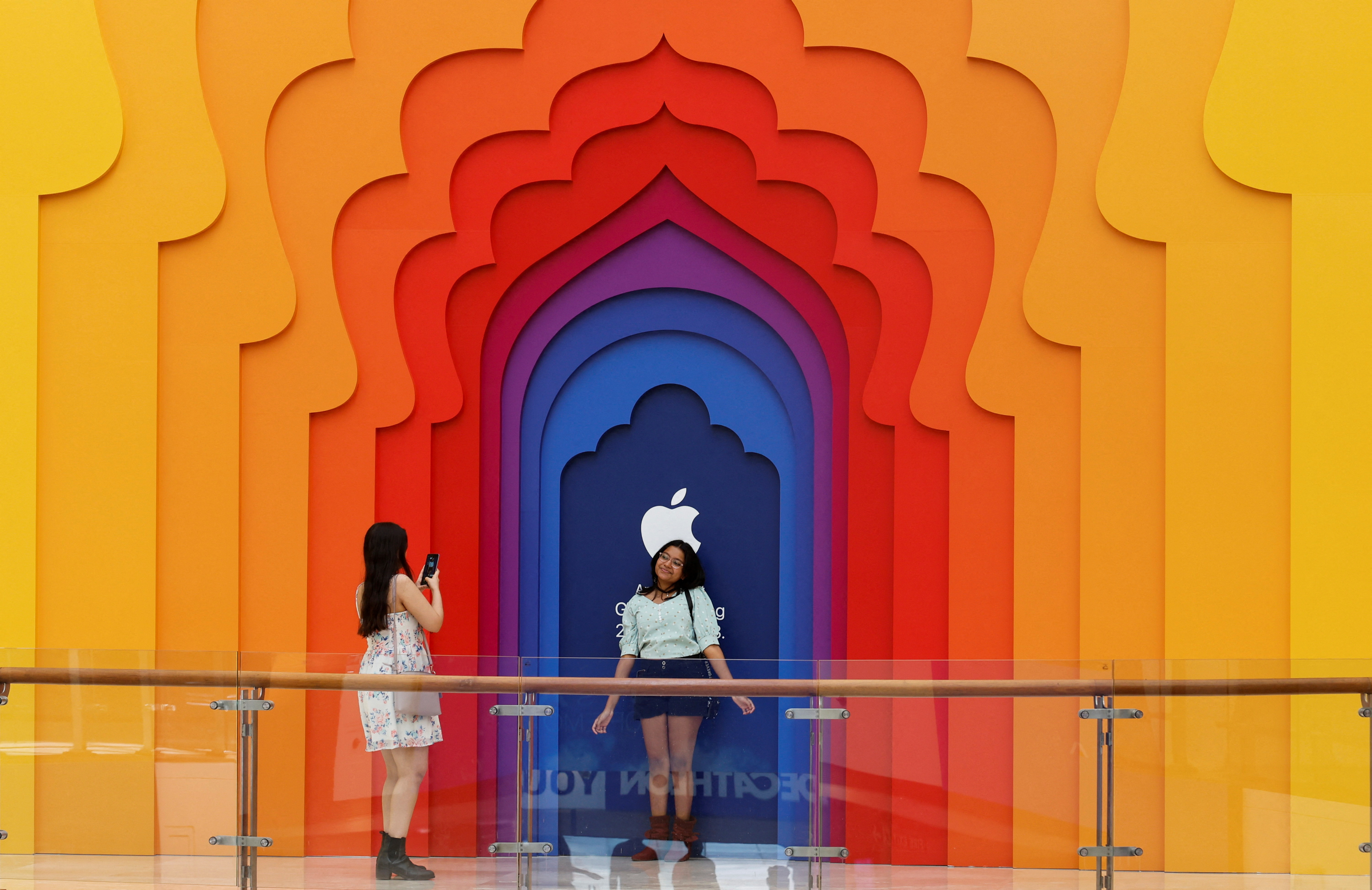 Una chica hace una foto a su amiga en el exterior de una tienda de Apple que se inaugurará próximamente en un centro comercial, en Nueva Delhi, India, el 12 de abril de 2023 (Reuters)