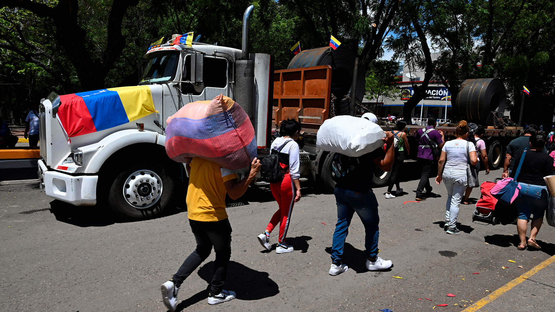 Un camión pasa junto a personas de a pie que lo hacen a diario (AFP)