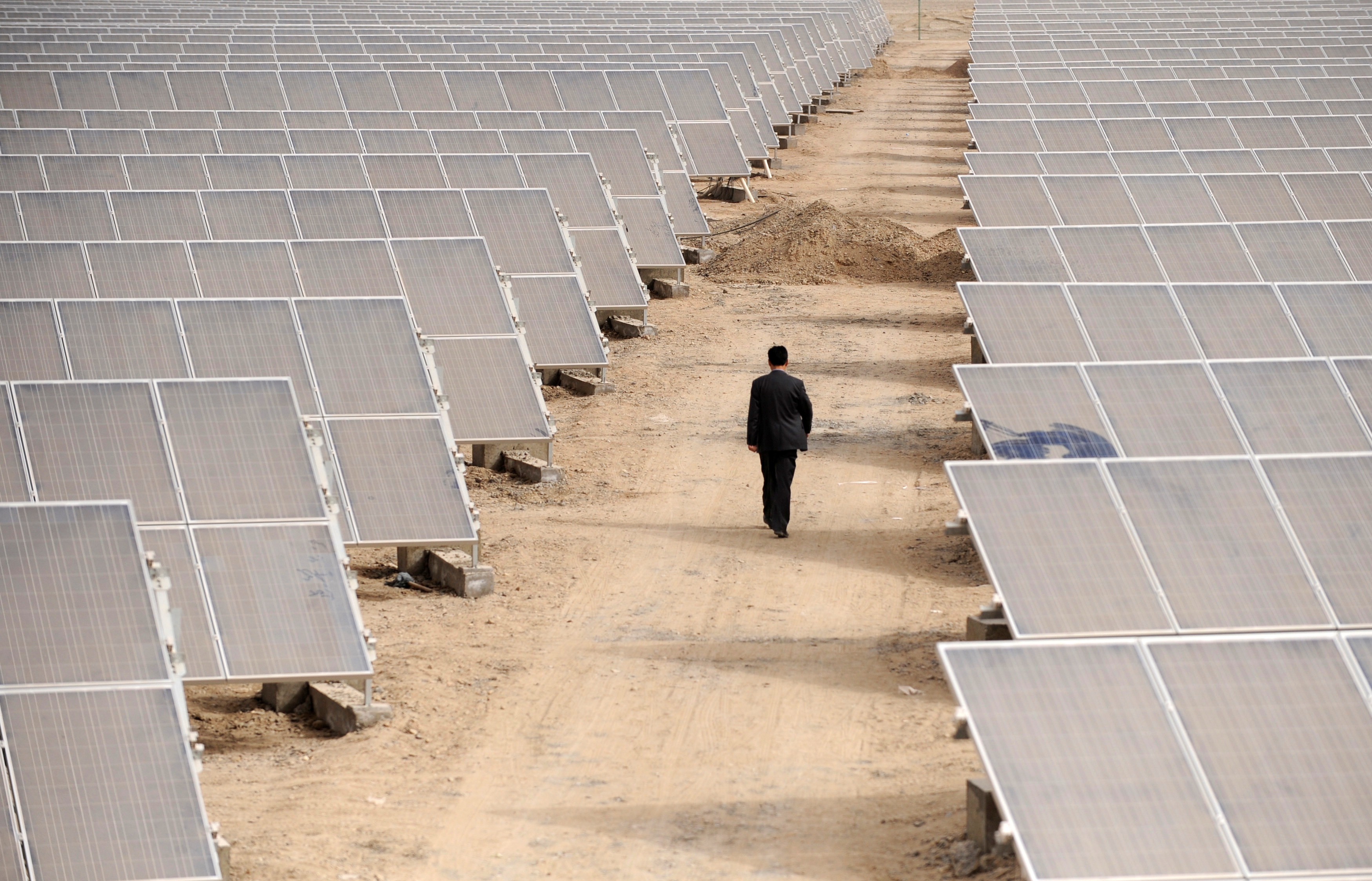 FOTO DE ARCHIVO: Un hombre camina a través de paneles solares en una planta de energía solar en construcción en Aksu, Región Autónoma Uigur de Xinjiang, 5 de abril de 2012. REUTERS/Stringer CHINA FUERA. SIN VENTAS COMERCIALES O EDITORIALES EN CHINA/Foto de archivo