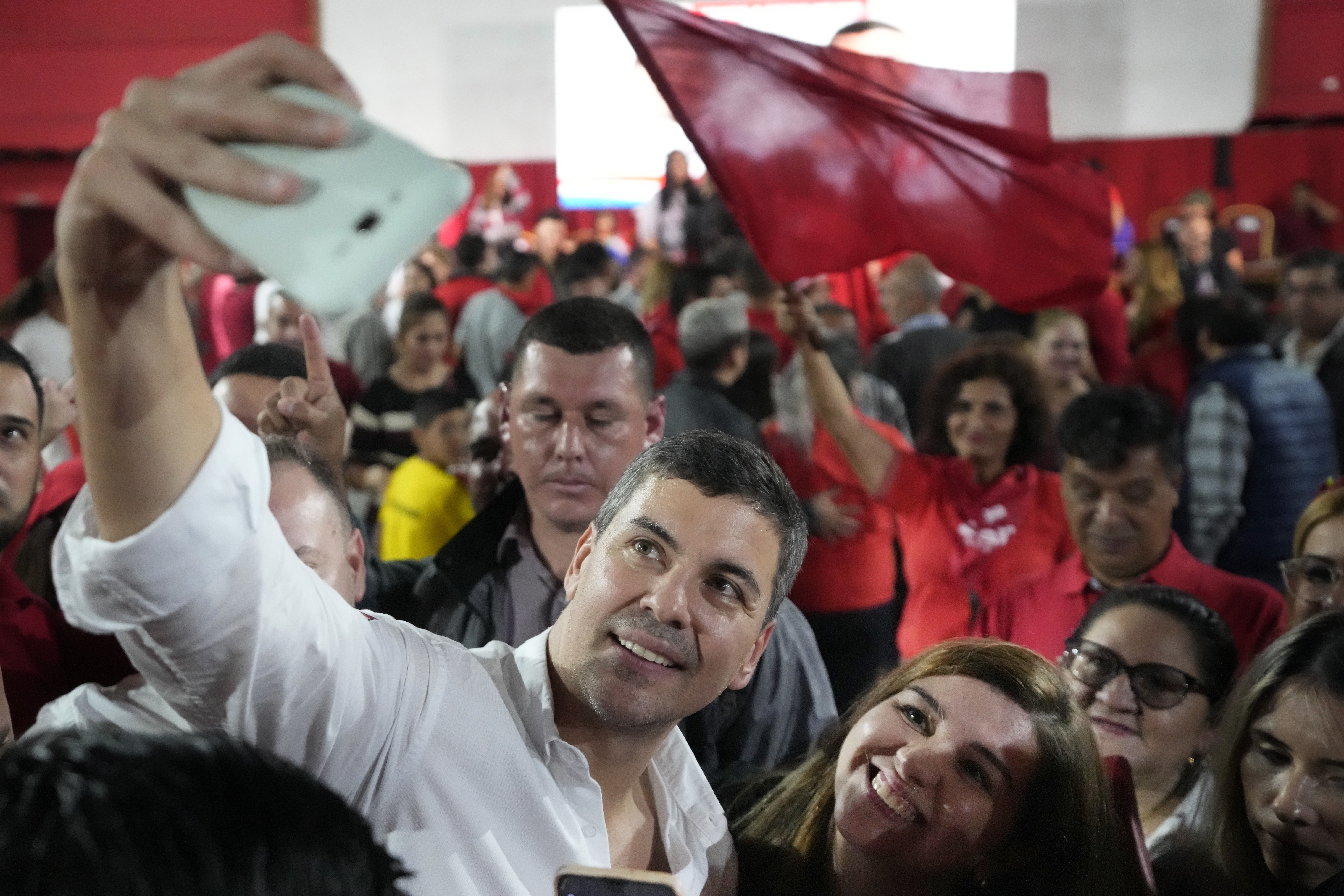 Santiago Peña, candidato presidencial por el gobernante Partido Colorado, se toma una selfie con un simpatizante durante un mitin en Villa Elisa, Paraguay (AP Foto/Jorge Saenz)