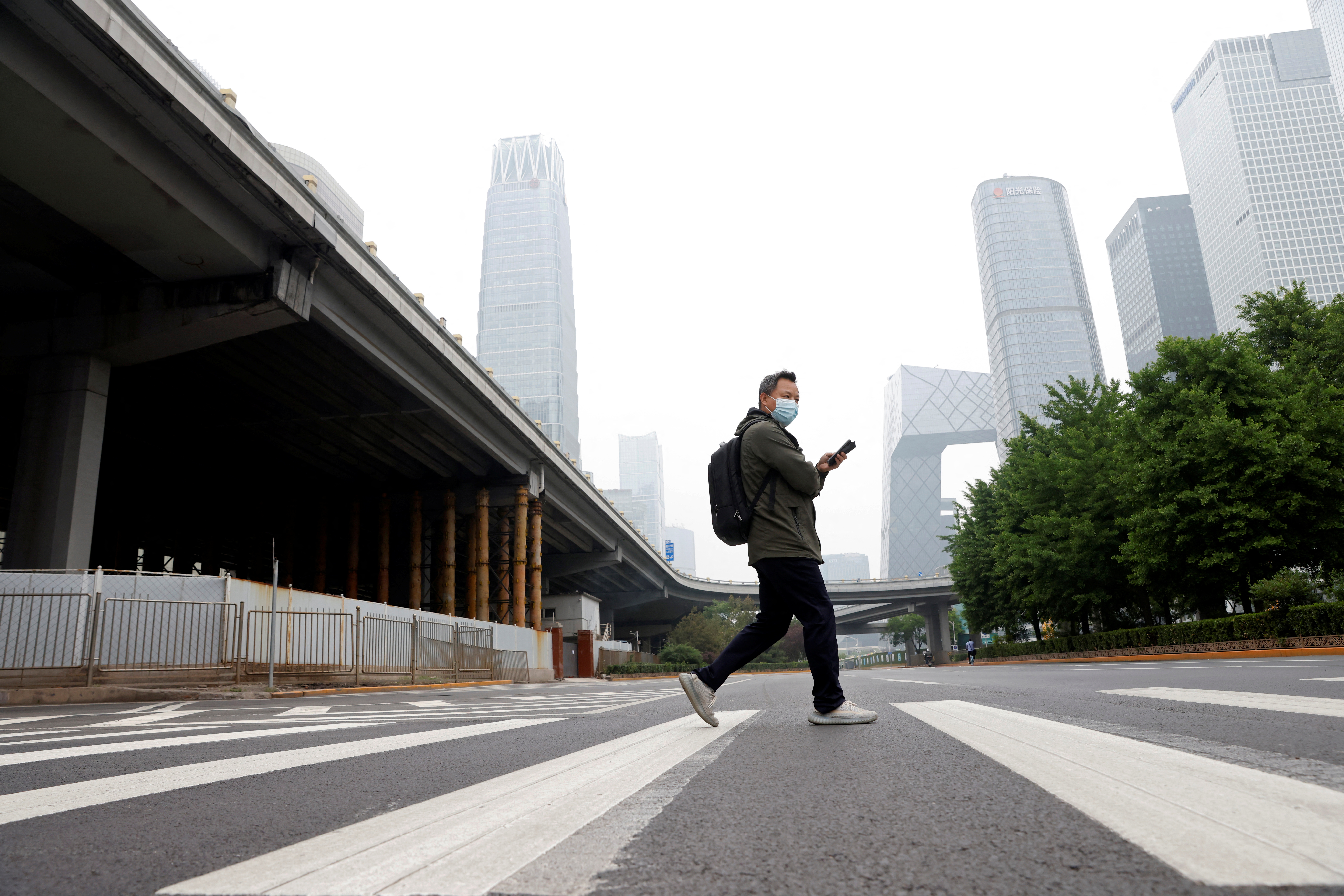 Un hombre con mascarilla cruza una calle en el Distrito Central de Negocios (CBD), en medio del brote de la enfermedad del coronavirus (COVID-19) en Beijing, China 10 de mayo de 2022. REUTERS/Carlos García Rawlins
