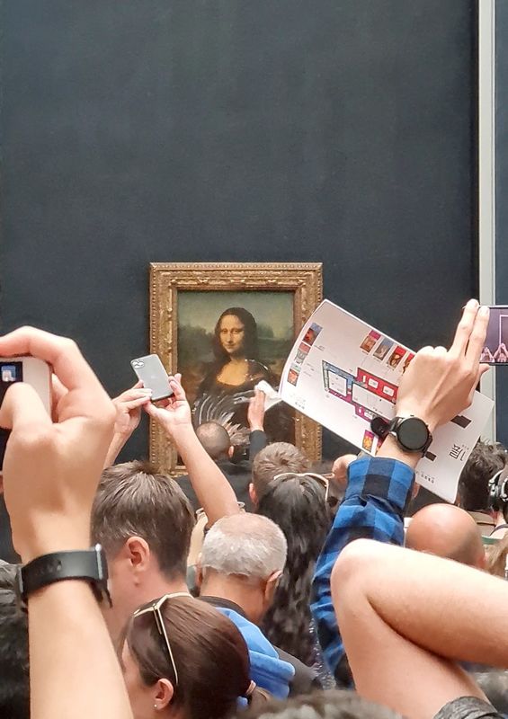 Un hombre trata de limpiar crema del cristal protector del cuadro "Mona Lisa" en el Museo de Lourve en París, Francia 29 de mayo de 2022 en esta captura de pantalla obtenida de un vídeo de las redes sociales. Twitter/@klevisl007/vía REUTERS
