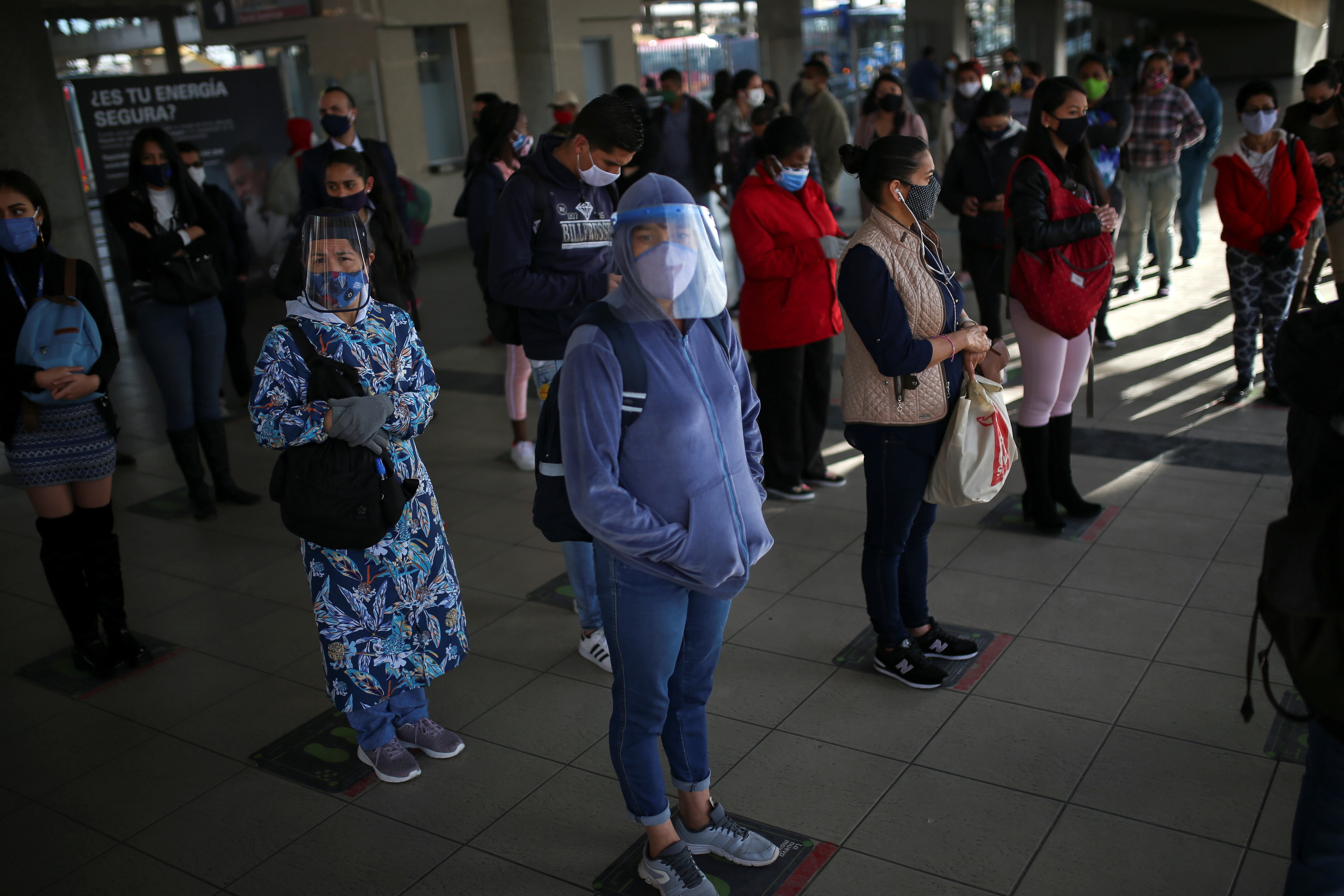 People wearing protective masks due to the ongoing coronavirus disease (COVID-19) outbreak, keep social distance as they wait for a bus inside a station of the TransMilenio public transport system after the mayor's office ended the quarantine in Bogota, Colombia August 27, 2020. REUTERS/Luisa Gonzalez