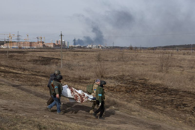 Militares ucranianos llevan un cadáver en camilla en la ciudad de Irpin, a las afueras de Kiev, Ucrania, el 12 de marzo de 2022 (REUTERS/Marko Djurica)