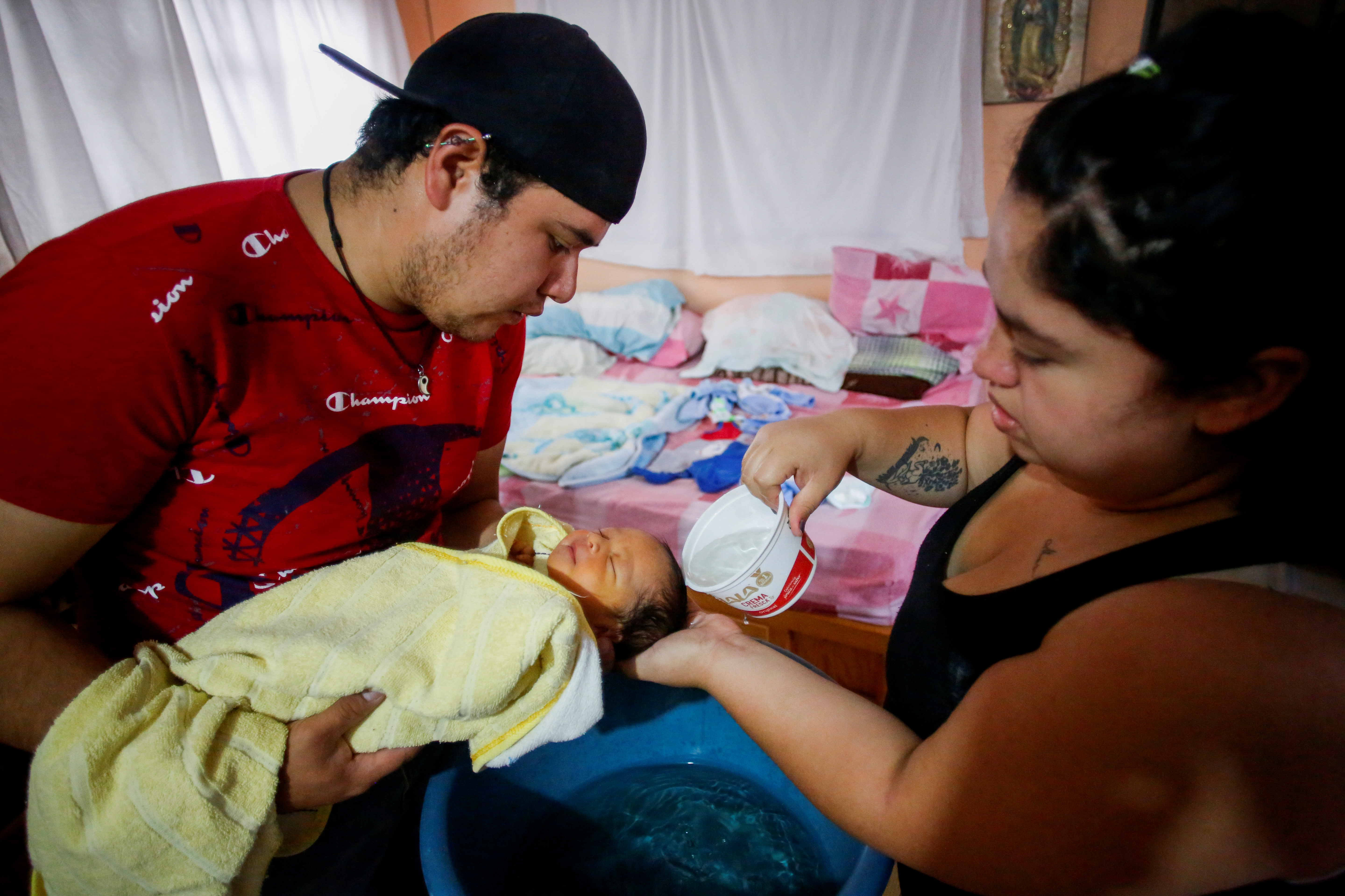 Miguel Flores Torres sostiene a su hijo recién nacido Sabino Yoehi Flores López con su esposa Karla López Rangel, quien lo dio a luz en su casa durante el brote de la enfermedad por coronavirus (COVID-19), lo baña en la casa de los padres de Rangel, donde se están quedando, en Iztapalapa, Ciudad de México, México, 31 de mayo de 2020. Foto: REUTERS / Gustavo Graf.