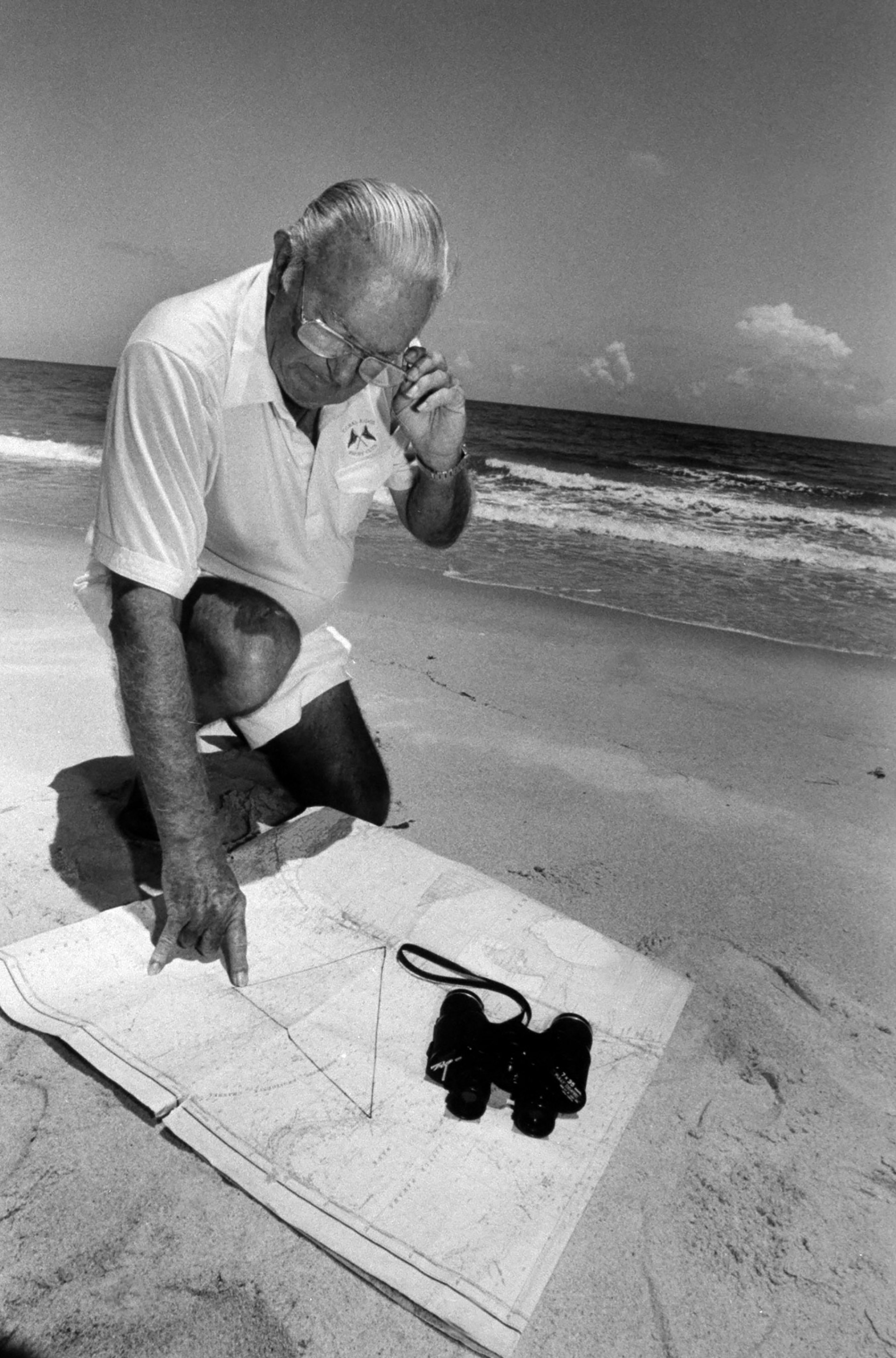 El exaviador de la Armada Dick Adams en la playa examinando el mapa que tiene un triángulo marcado sobre la región del Atlántico para indicar el Triángulo de las Bermudas (Photo by Acey Harper/Getty Images)