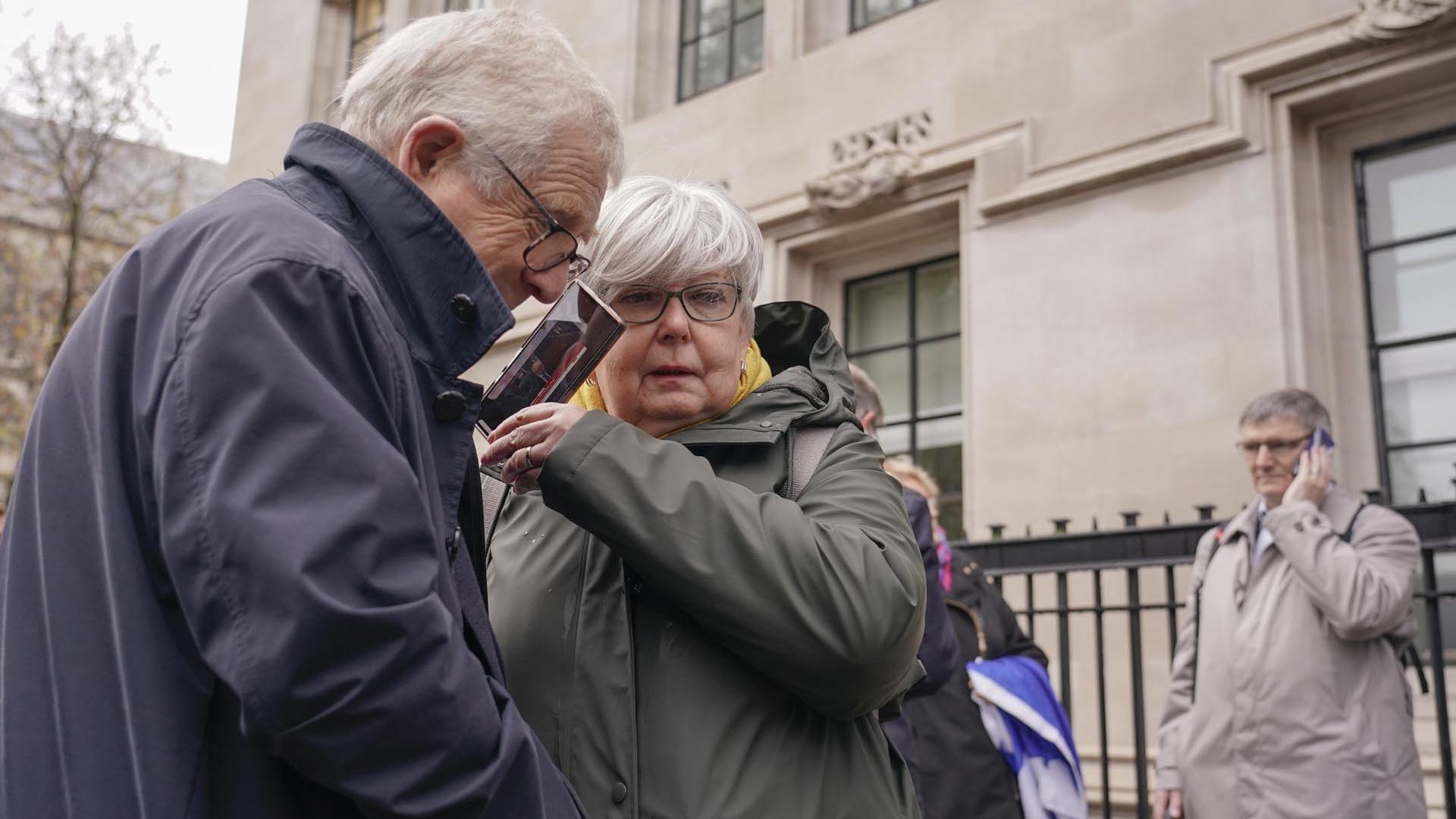 Los manifestantes sostienen sus teléfonos mientras escuchan el veredicto sobre el referéndum de independencia de Escocia, frente a la Corte Suprema, en Londres. (AP Photo/Alberto Pezzali)

