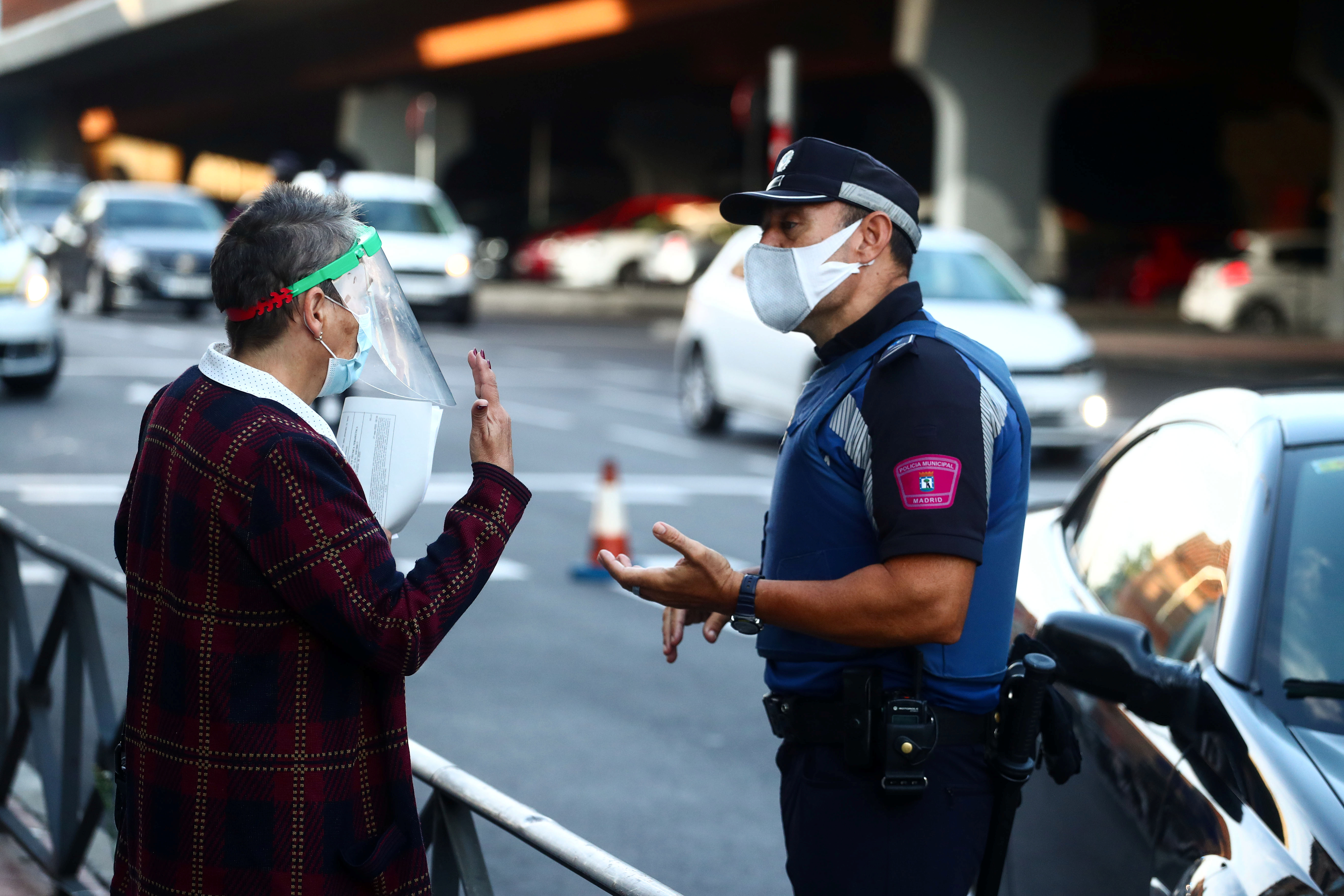 Un policía local habla con una mujer en el barrio de Vallecas durante el primer día de un cierre parcial entre y dentro de áreas en seis distritos en medio del brote de la enfermedad por coronavirus (COVID-19) en Madrid, España. REUTERS/Sergio Perez