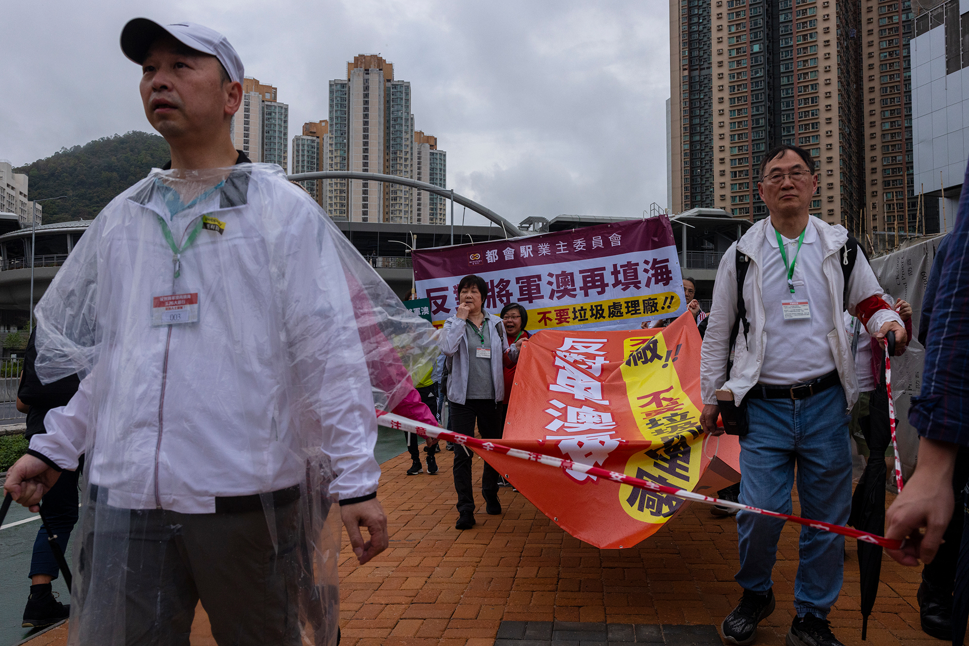 Manifestantes caminan dentro de una línea de cordón con etiquetas numéricas durante una manifestación en Hong Kong, el domingo 26 de marzo de 2023.  (AP Photo/Louise Delmotte)

