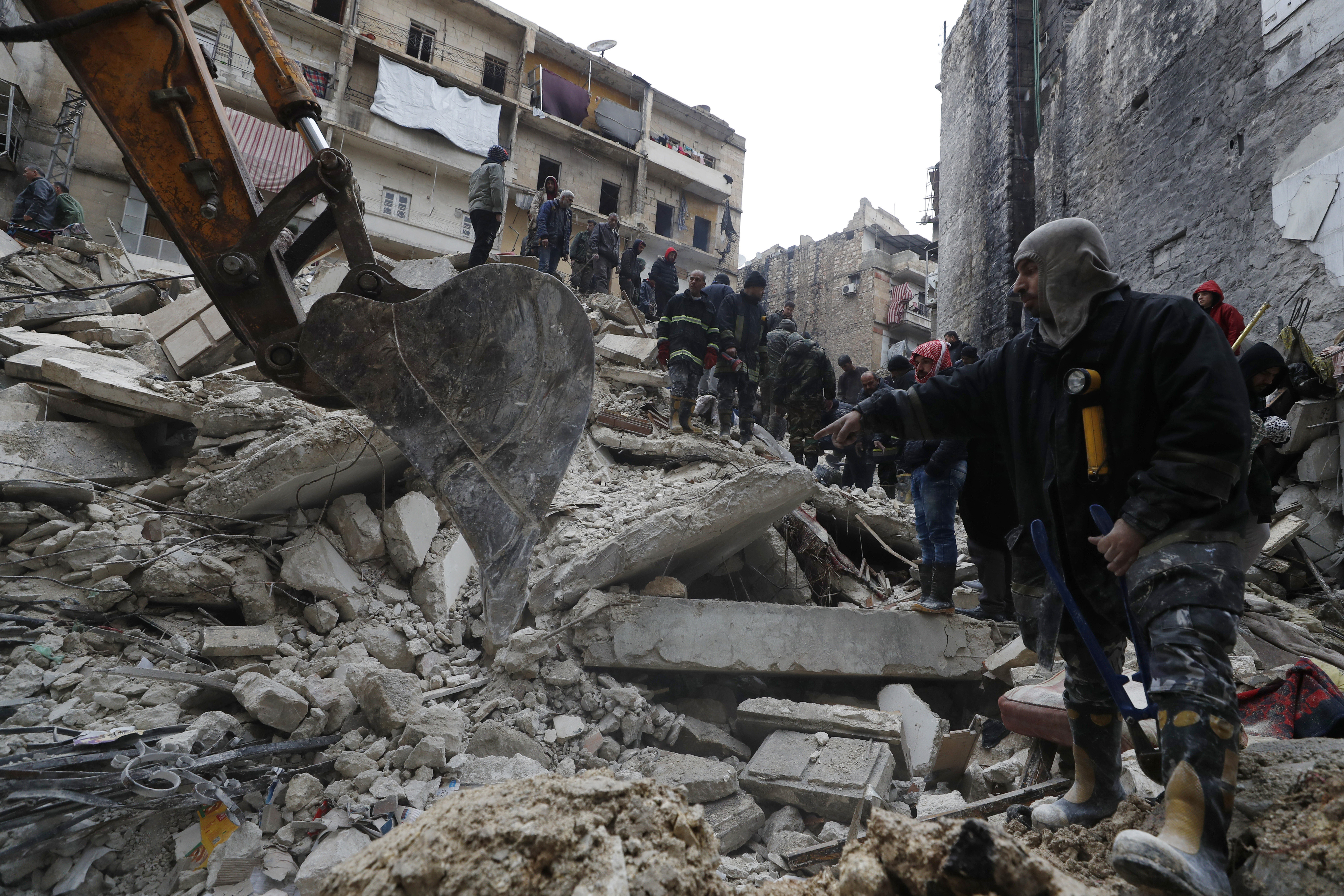 Trabajadores de protección civil y fuerzas de seguridad de Siria buscan entre los escombros de un edificio que se desplomó, el lunes 6 de febrero de 2023, en Alepo, Siria (AP Foto/Omar Sanadiki)