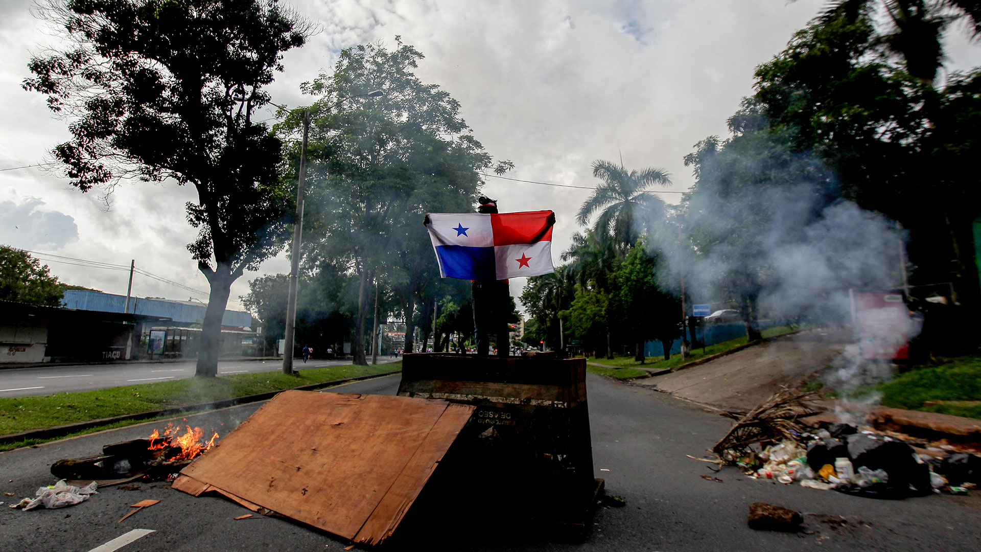Un manifestante sostiene una bandera de Panamá durante un corte de una avenida, en las protestas contra la corrupción y el costo del vida en el país (ROGELIO FIGUEROA / AFP)