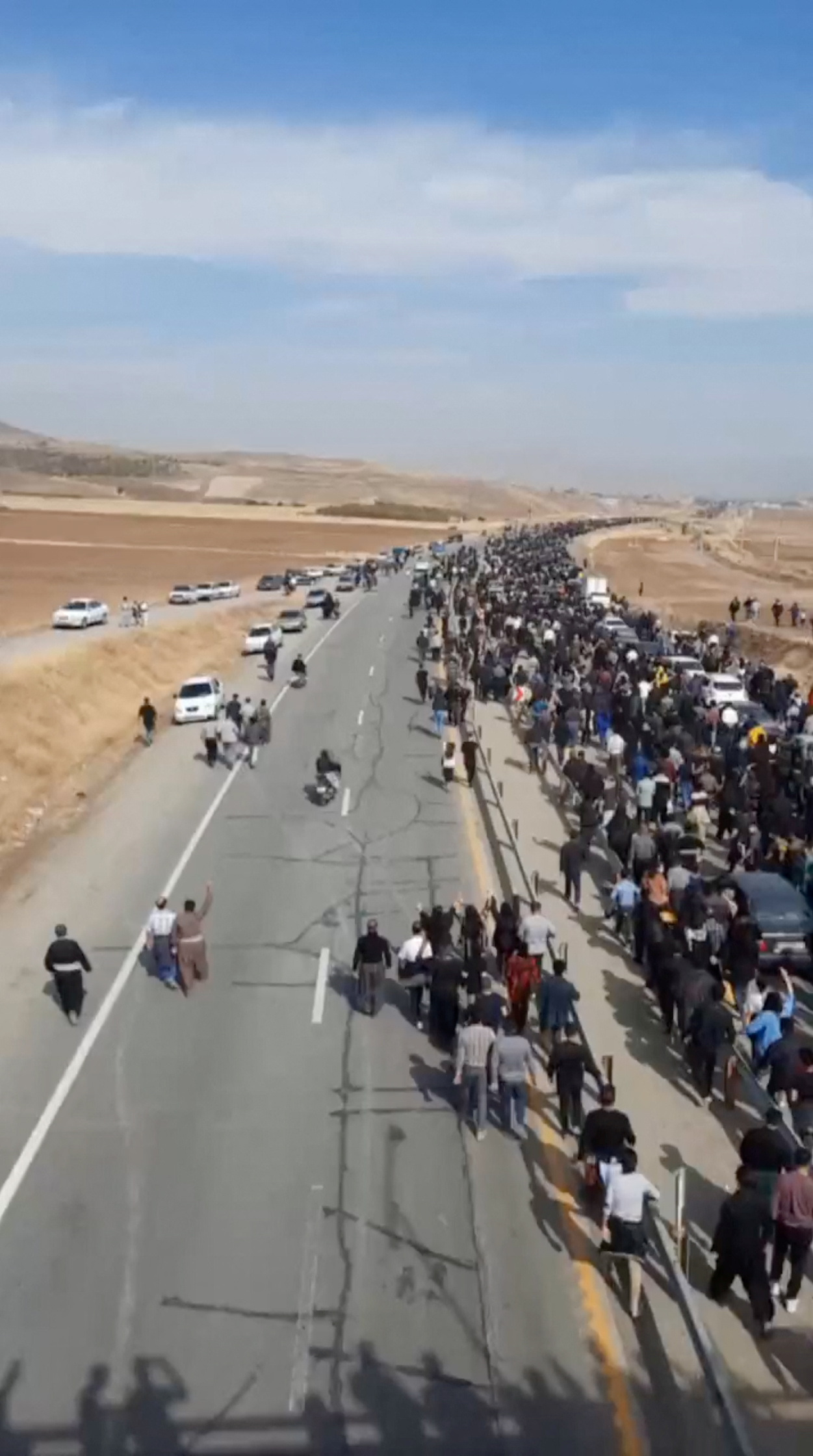 La gente marcha por la carretera hacia el cementerio de Aychi, donde está enterrado Mahsa Amini, cerca de Saqez, Irán (REUTERS)