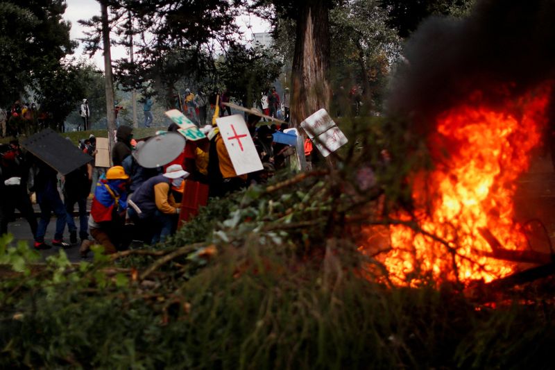 Se ven ramas quemándose mientras los manifestantes usan escudos improvisados durante una protesta antigubernamental, en Quito (REUTERS /Adriano Machado)