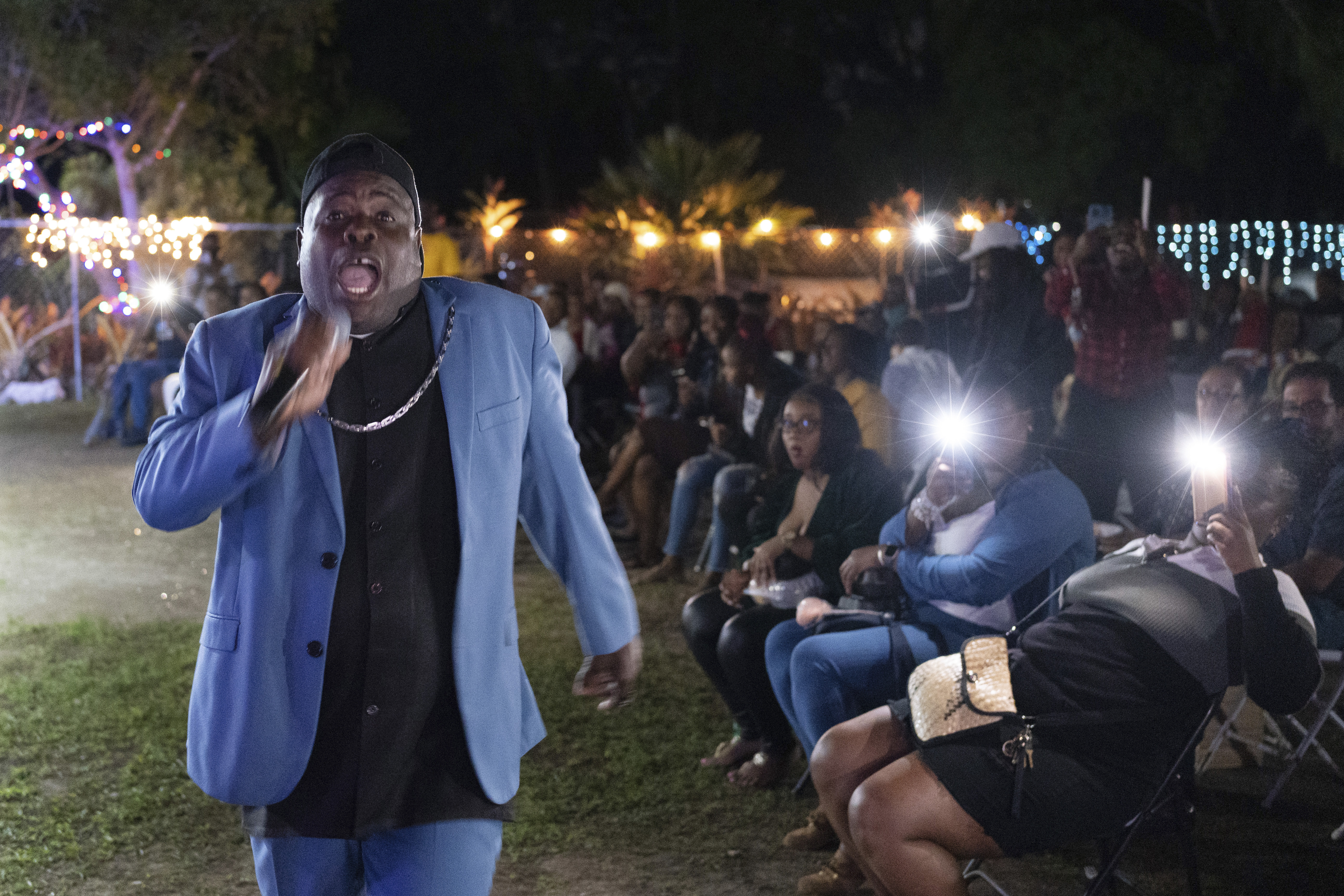 El obispo Lawrence Rolle canta frente a niños y adultos en la Academia Preparatoria del Monte Carmelo, el jueves 8 de diciembre de 2022, en Nasáu, Bahamas. (AP Foto/Ken Sweet)