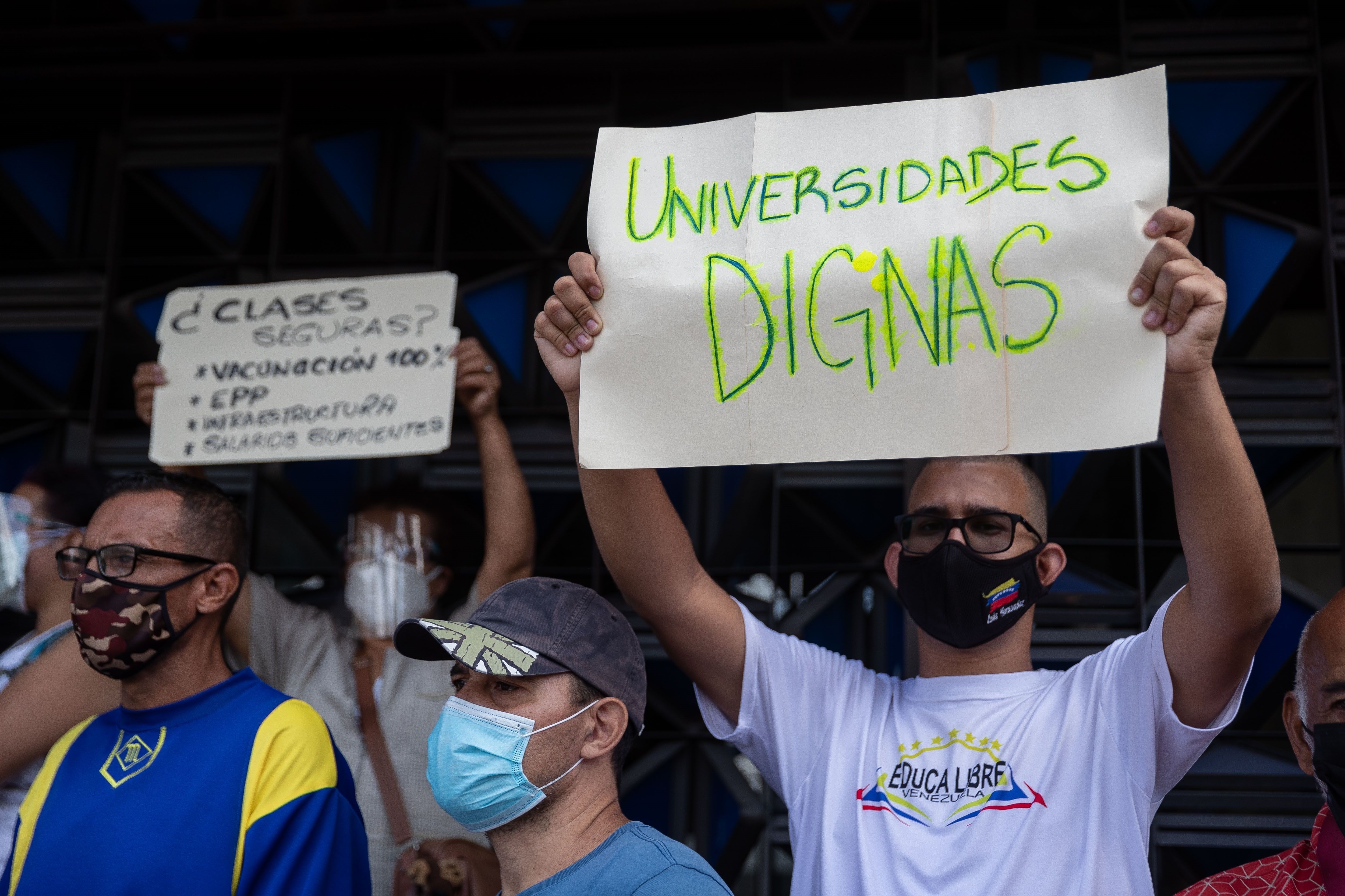 Un hombre carga una pancarta que dice "Universidades dignas" durante una protesta por mejores condiciones laborales frente al Ministerio de Educación hoy en Caracas (EFE/Rayner Peña)