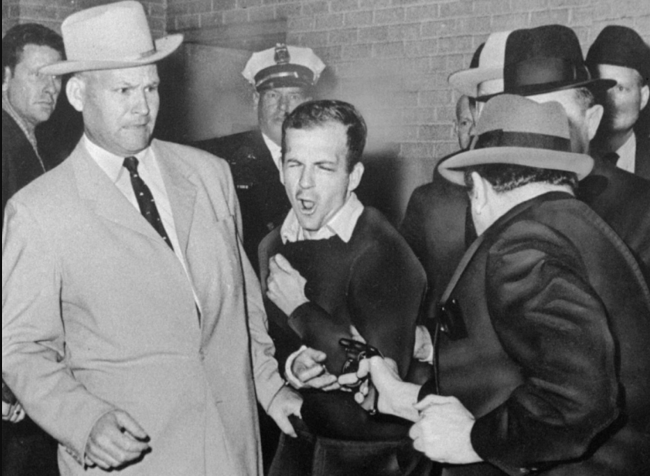 Lee Harvey Oswald winces as Dallas night club owner Jack Ruby shoots at Dallas police headquarters on Nov. 24, 1963 (AP Photo/Dallas Times-Herald, Bob Jackson)