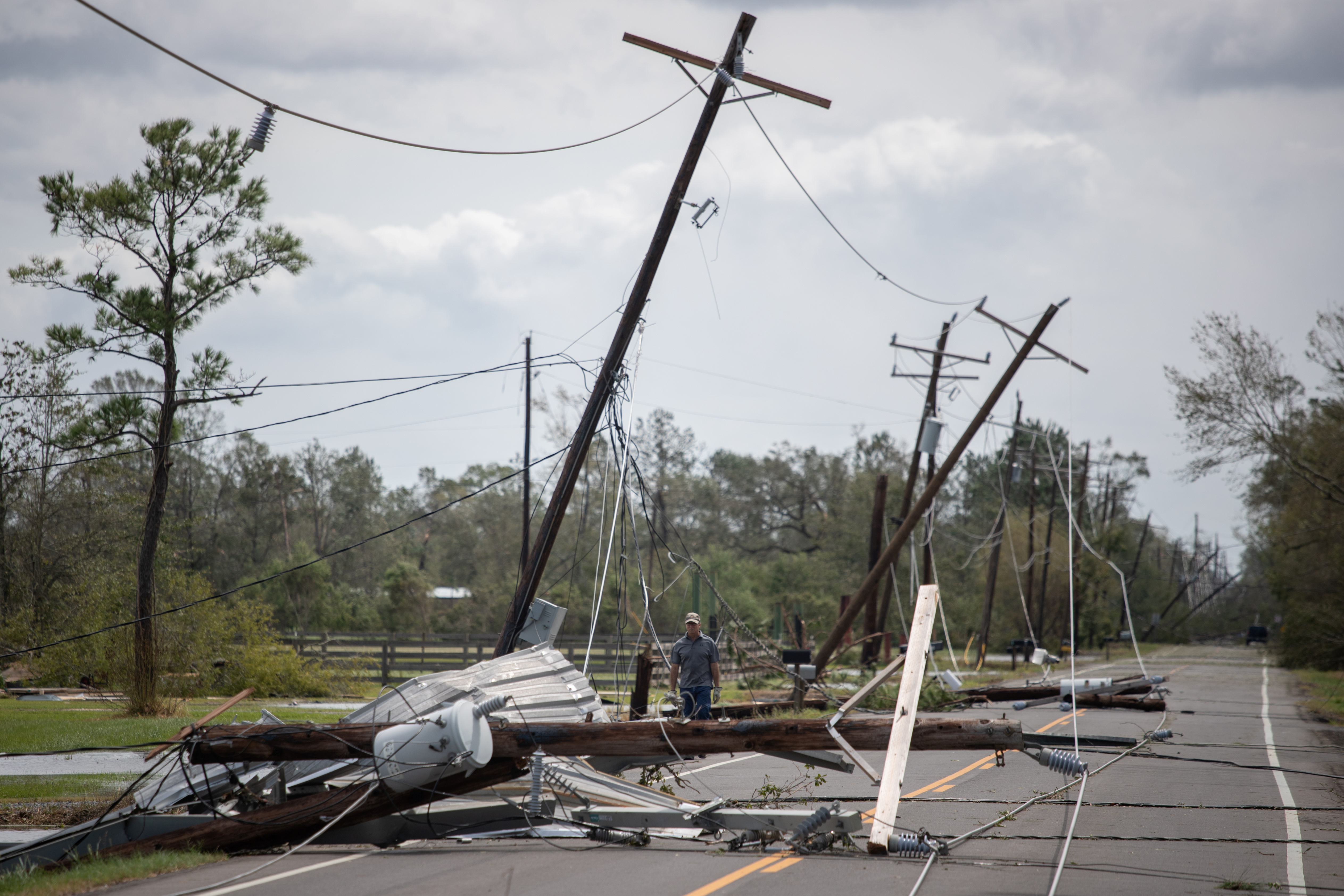 Un hombre pasa por delante de cables eléctricos caídos para llegar a su residencia tras el huracán Laura en Sulphur, Louisiana, el 27 de agosto de 2020 (REUTERS/Adrees Latif(