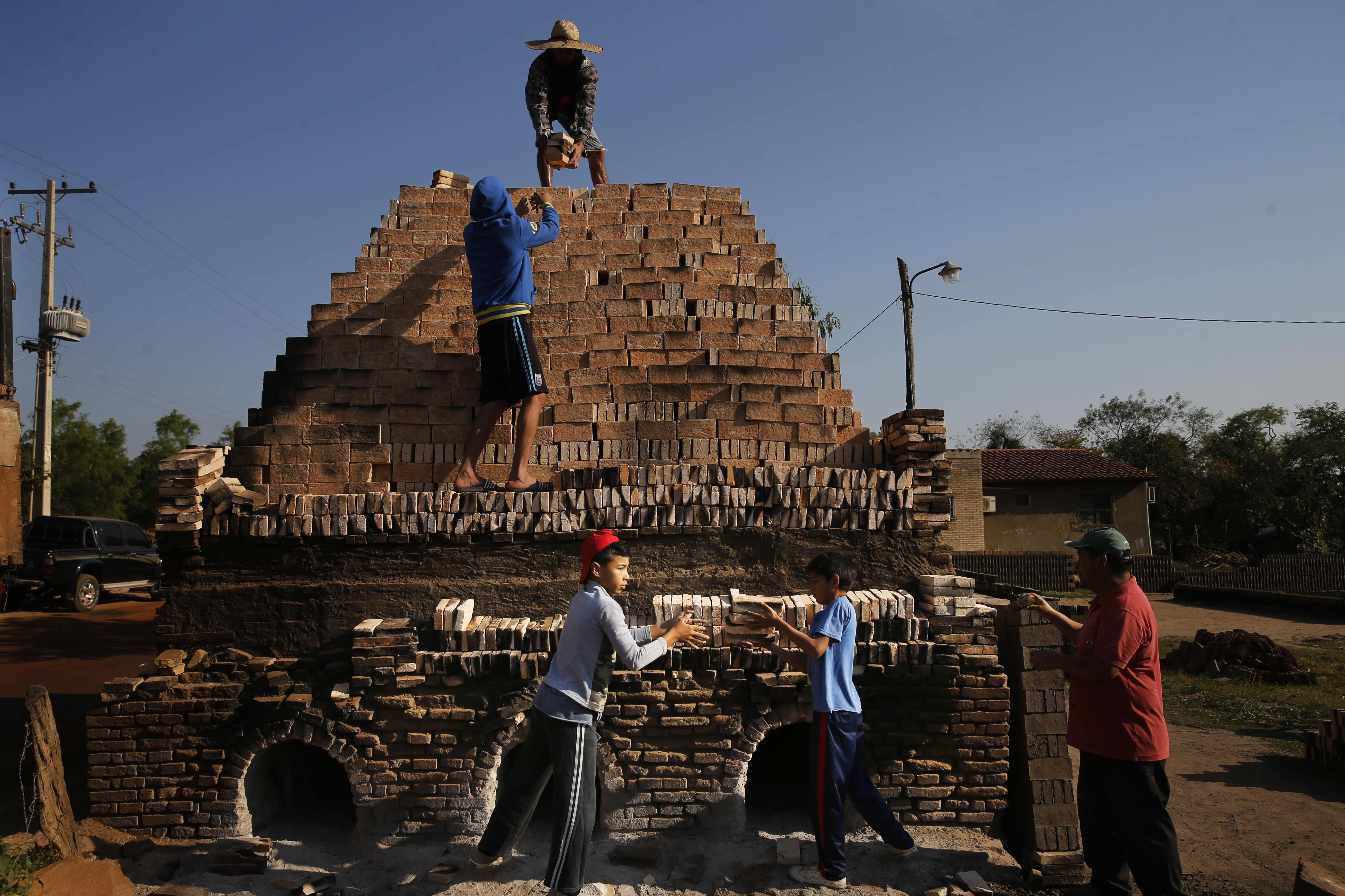 Los niños trabajan con sus familiares para cargar un horno con ladrillos de arcilla en Tobati, Paraguay, el viernes 4 de septiembre de 2020. En muchas de las pequeñas fábricas de ladrillos de Tobati, los lugareños comienzan a trabajar a una edad temprana para complementar los ingresos familiares.