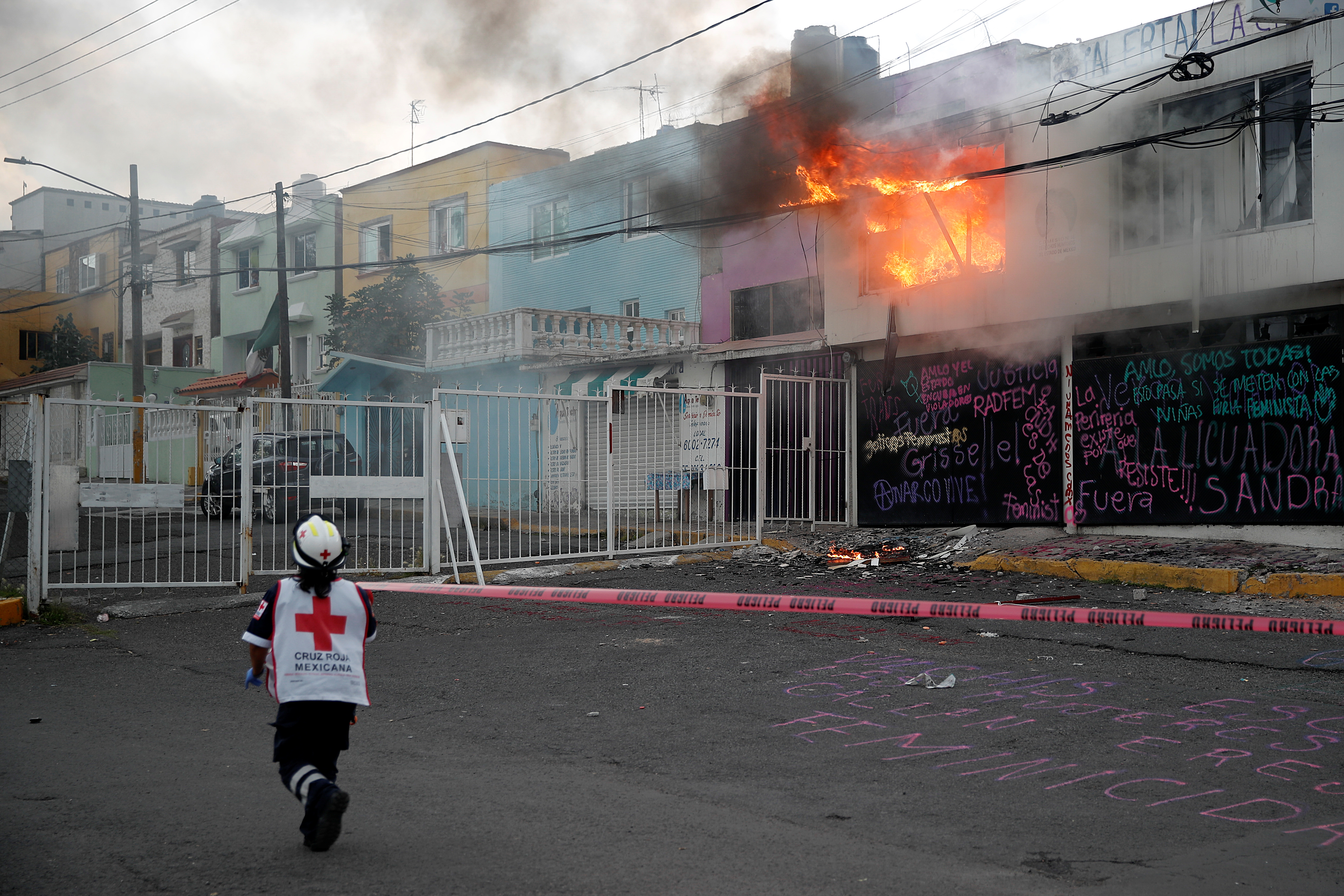 Un miembro de la Cruz Roja pasa junto a un incendio que estalló después de que miembros de un colectivo feminista vandalizaran las instalaciones de la comisión de derechos humanos del estado de México, en apoyo a las víctimas de violencia de género, en Ecatepec, Estado de México, México el 11 de septiembre de 2020.