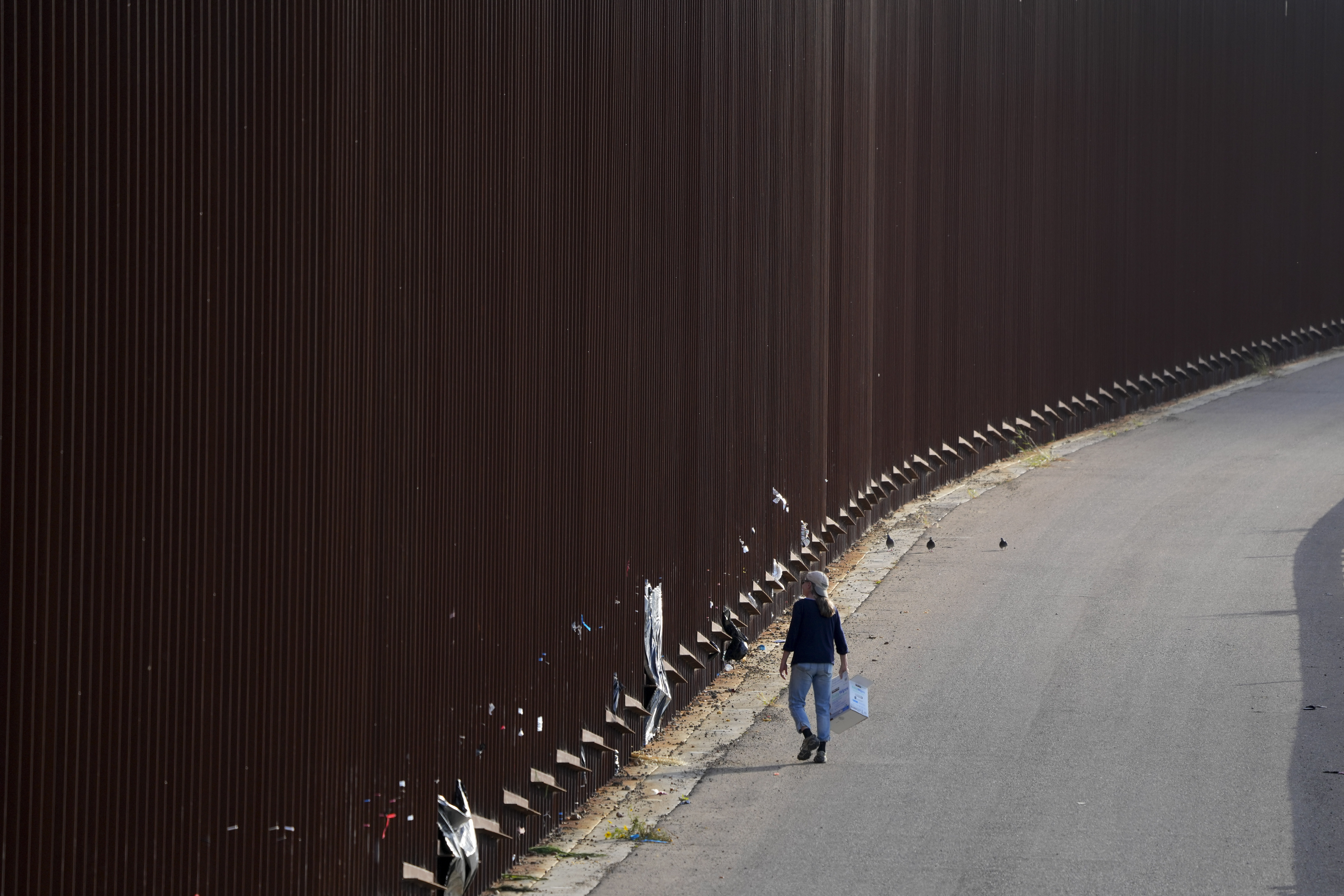 Un voluntario camina al lado del muro fronterizo en San Diego (AP Foto/Gregory Bull)