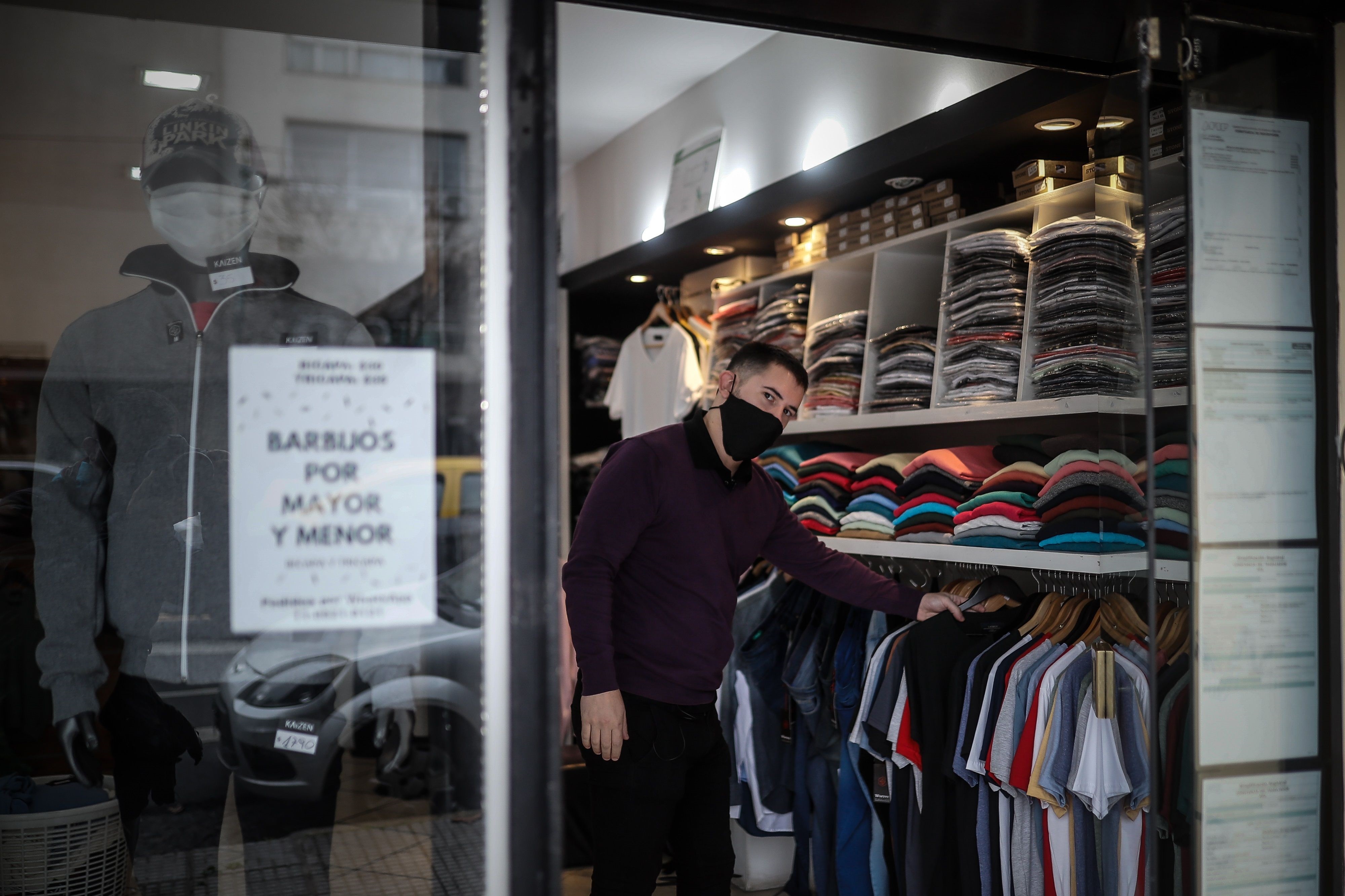 Un hombre acomoda ropa en su local hoy lunes, luego que el gobierno permitiera la apertura de zapaterías y locales textiles en Buenos Aires. EFE/Juan Ignacio Roncoroni
