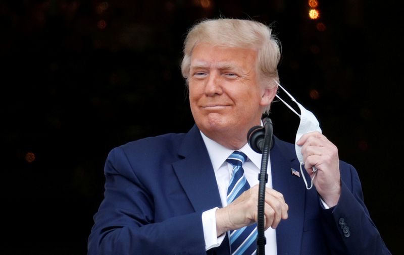 El presidente de Estados Unidos, Donald Trump, se quita la mascarilla al salir al balcón de la Casa Blanca para hablar con los partidarios reunidos en la Casa Blanca, en Washington, EEUU, 10 de octubre de 2020. REUTERS/Tom Brenner