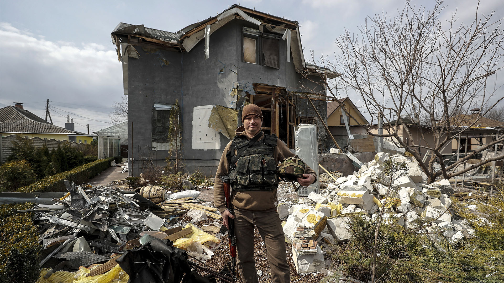 Vlad Malyshev posa con su equipamiento militar ante los restos de su casa, destruida por un misil que impacto contra ella y casi acaba también con él. EFE/Manuel Bruque
