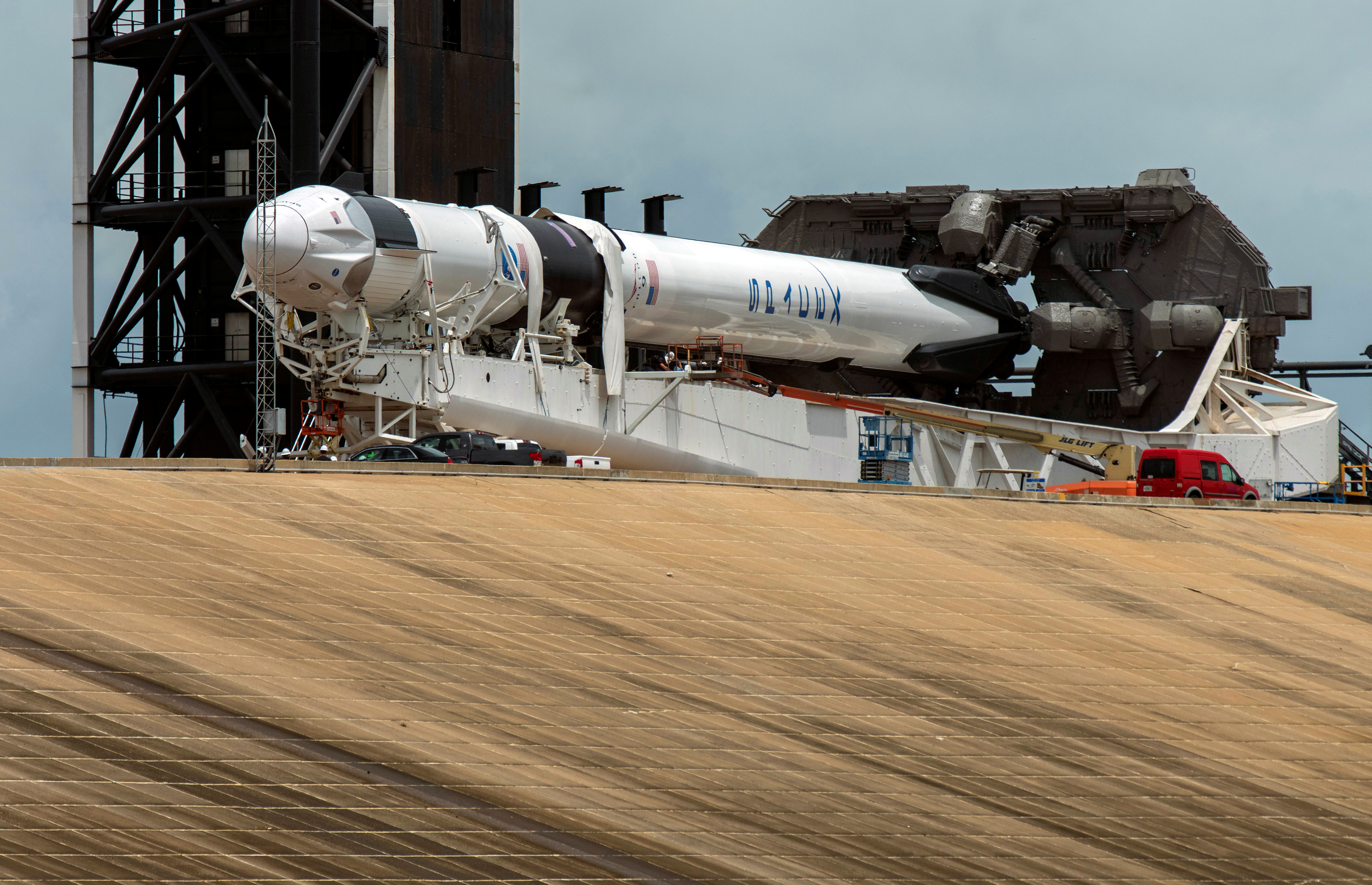 Técnicos trabajan en el SpaceX Crew Dragon, acoplado a un cohete propulsor Falcon 9, un día antes de la fecha fijada para el lanzamiento. 
