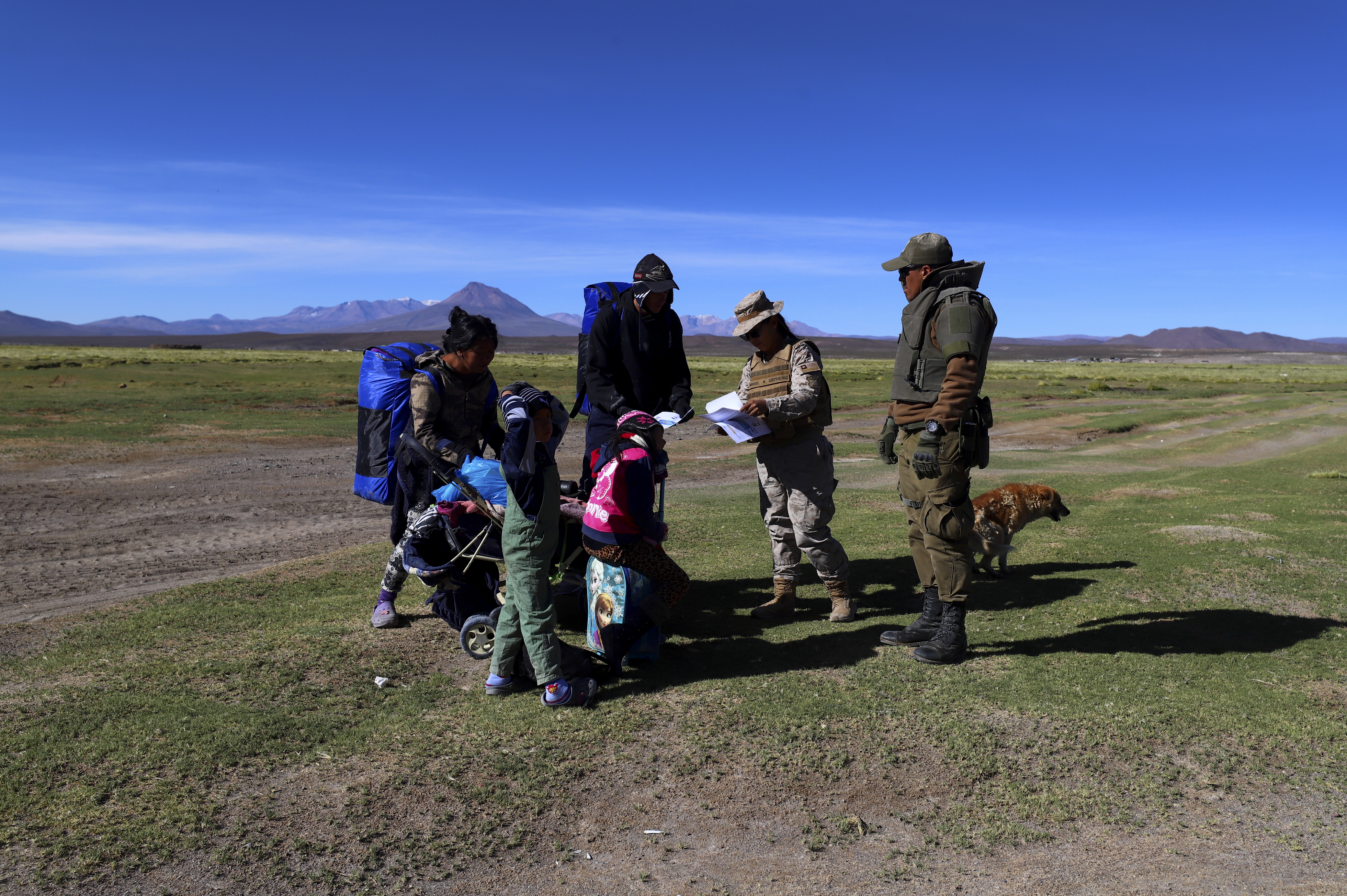 Chilean soldiers talk with migrants before taking them to a shelter where police search them, near Colchane, Chile, Wednesday, March 1, 2023. The government announced an increased military presence on the border with Peru and Bolivia. as a measure to curb illegal immigration.  (AP Photo/Ignacio Munoz)
