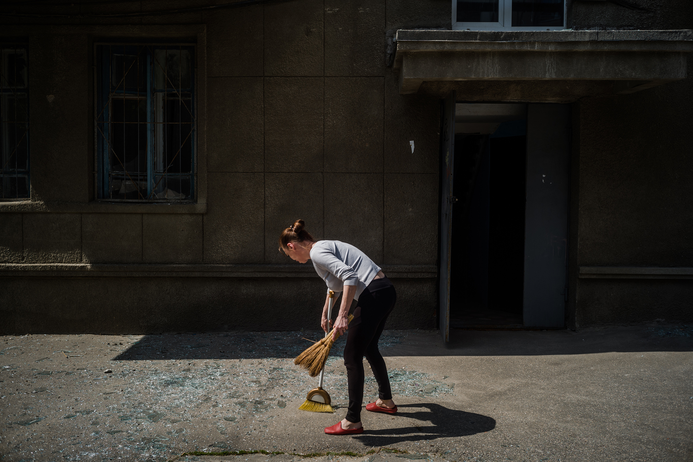 Tatiana Andrienko barre vidrios de la acera frente a su edificio de apartamentos el 3 de mayo después de que un cohete ruso impactara en un área cercana en Kharkiv. (Wojciech Grzedzinski para The Washington Post)