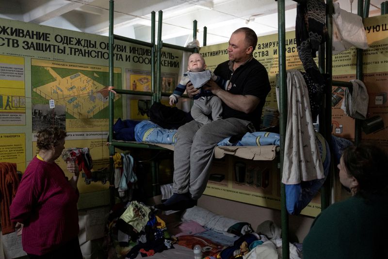 Un uomo trasporta suo figlio all'interno di un rifugio antiaereo presso l'impianto chimico di Azot, dove le persone si nascondono dai bombardamenti dall'inizio della guerra, a Severodonetsk