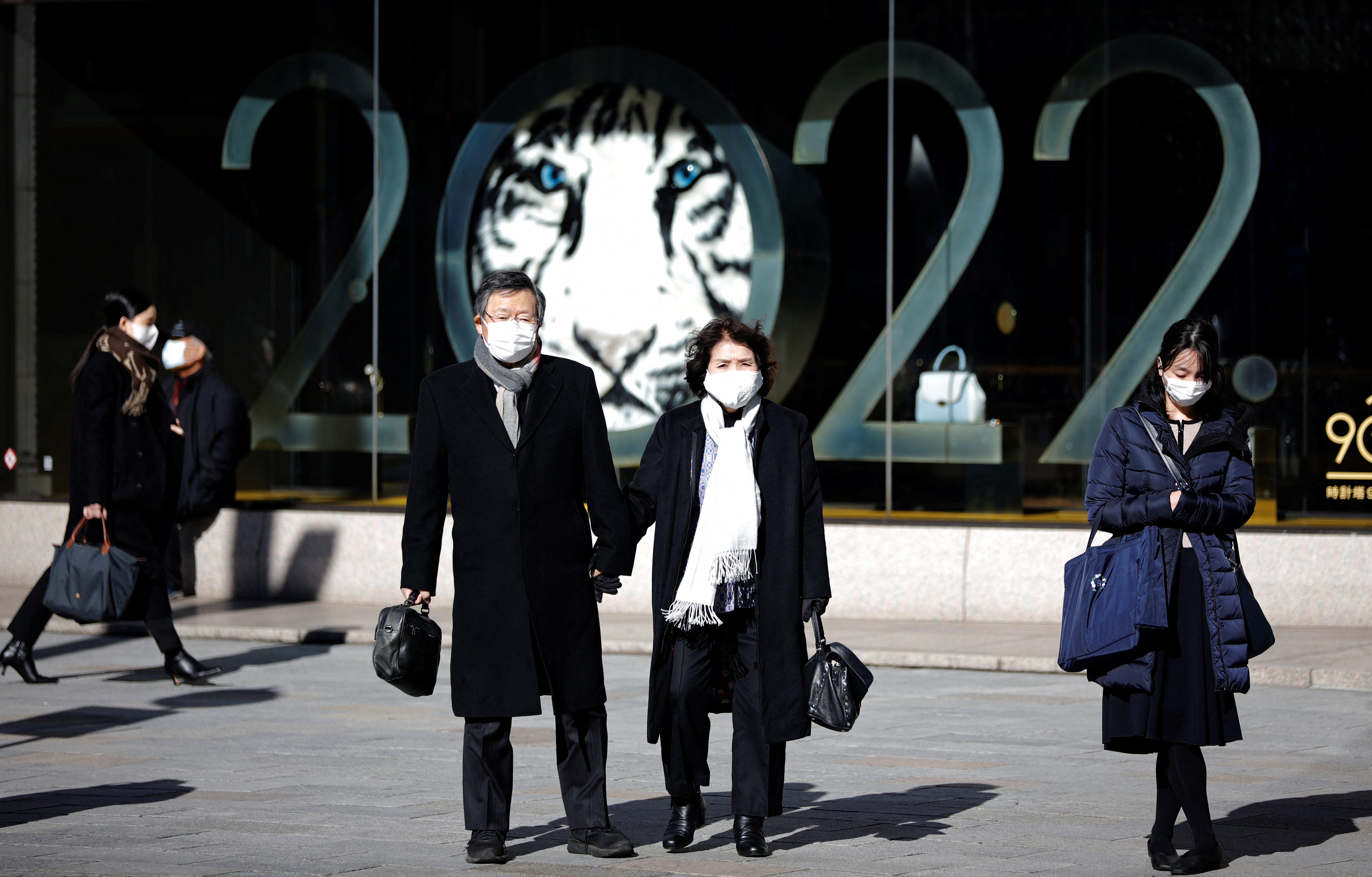 Personas con máscaras protectoras, en medio del brote de la enfermedad del coronavirus (COVID-19), se paran frente a un escaparate de unos grandes almacenes en un distrito comercial de Tokio, Japón, el 18 de enero de 2022. 2022 es el Año Nuevo Lunar chino del Tigre. REUTERS/Kim Kyung-Hoon