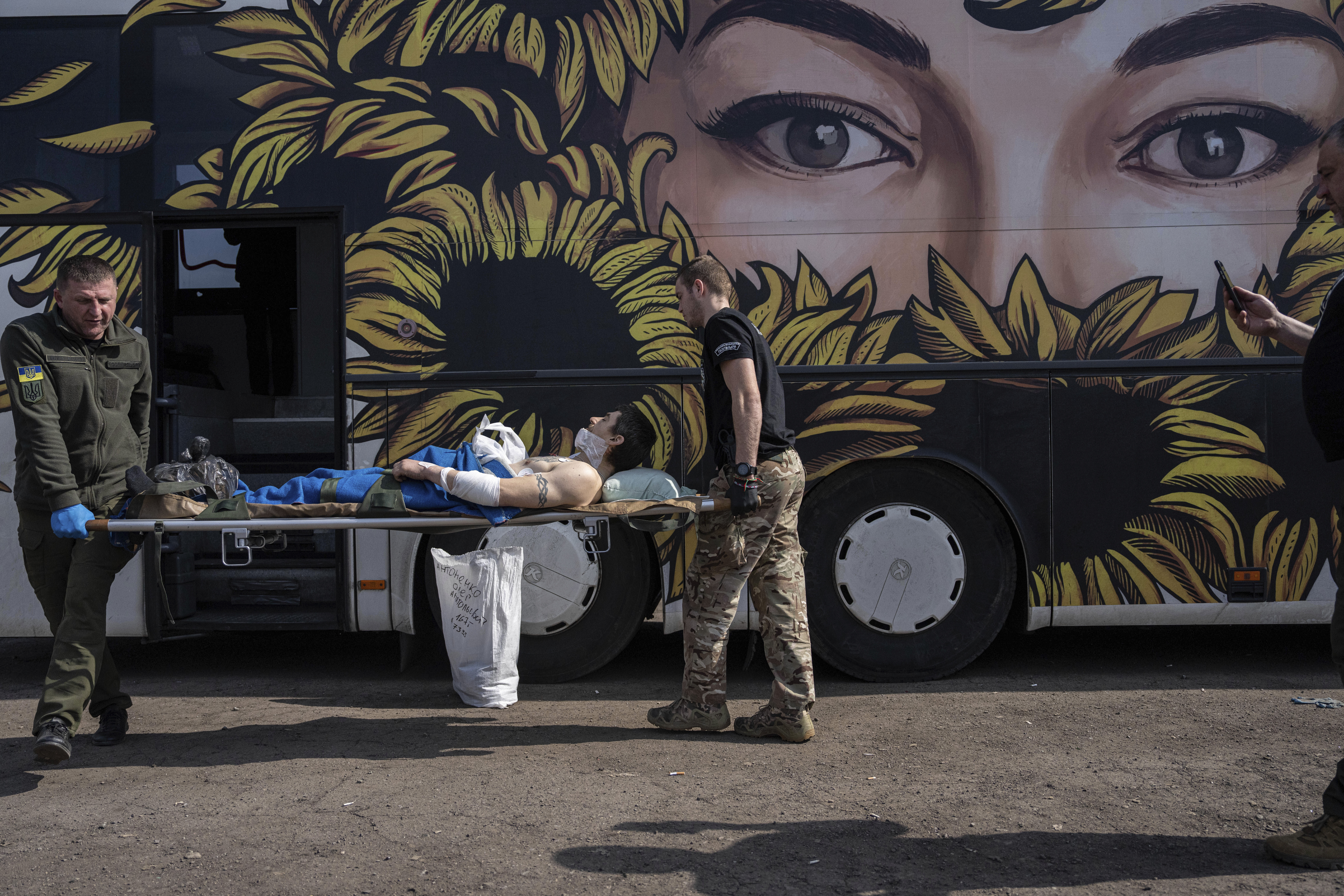 Voluntarios de la organización paramédica de transporte Hospitallers llevan a Oleksandr, un soldado ucraniano herido, a un autobús medicalizado durante una evacuación en la región de Donetsk, Ucrania, el miércoles 22 de marzo de 2023. (AP Foto/Evgeniy Maloletka)