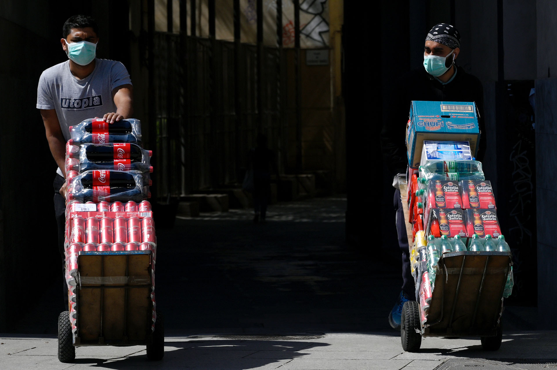 Dos proveedores de bebidas llevan su carga en una calle de Barcelona, España.