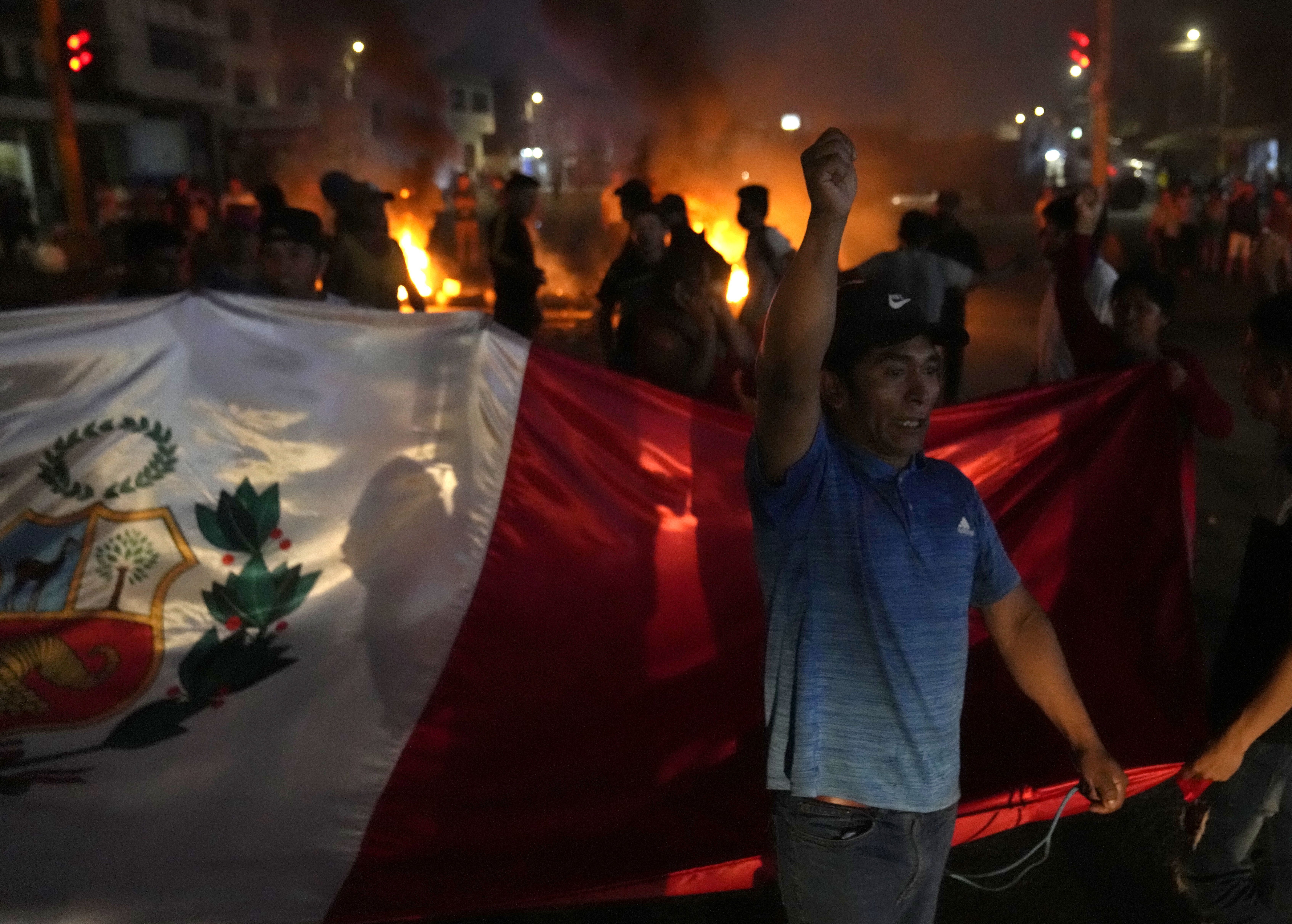 Un manifestante lanza proclamas contra el gobierno mientras otros llevan una bandera nacional durante el bloqueo de la autopista Panamericana Norte en Chao, Perú, el viernes 17 de febrero de 2023. Perú está inmerso en una crisis política con manifestaciones que piden la renuncia de la presidenta, Dina Boluarte, y la disolución del Congreso después de que el expresidente Pedro Castillo fuera destituido y detenido por intentar disolver el Parlamento en diciembre. Las manifestaciones han supuesto recurrentes bloqueos de carretera como ocurrió el viernes 3 de marzo de 2023 en una de las vías principales de acceso a la capital Lima. (AP Photo/Martin Mejia)