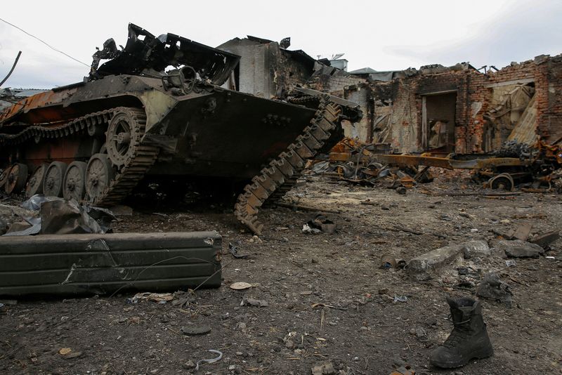 Un vehículo de combate acorazado ruso destruido junto a las ruinas de varios edificios en  Trostianets