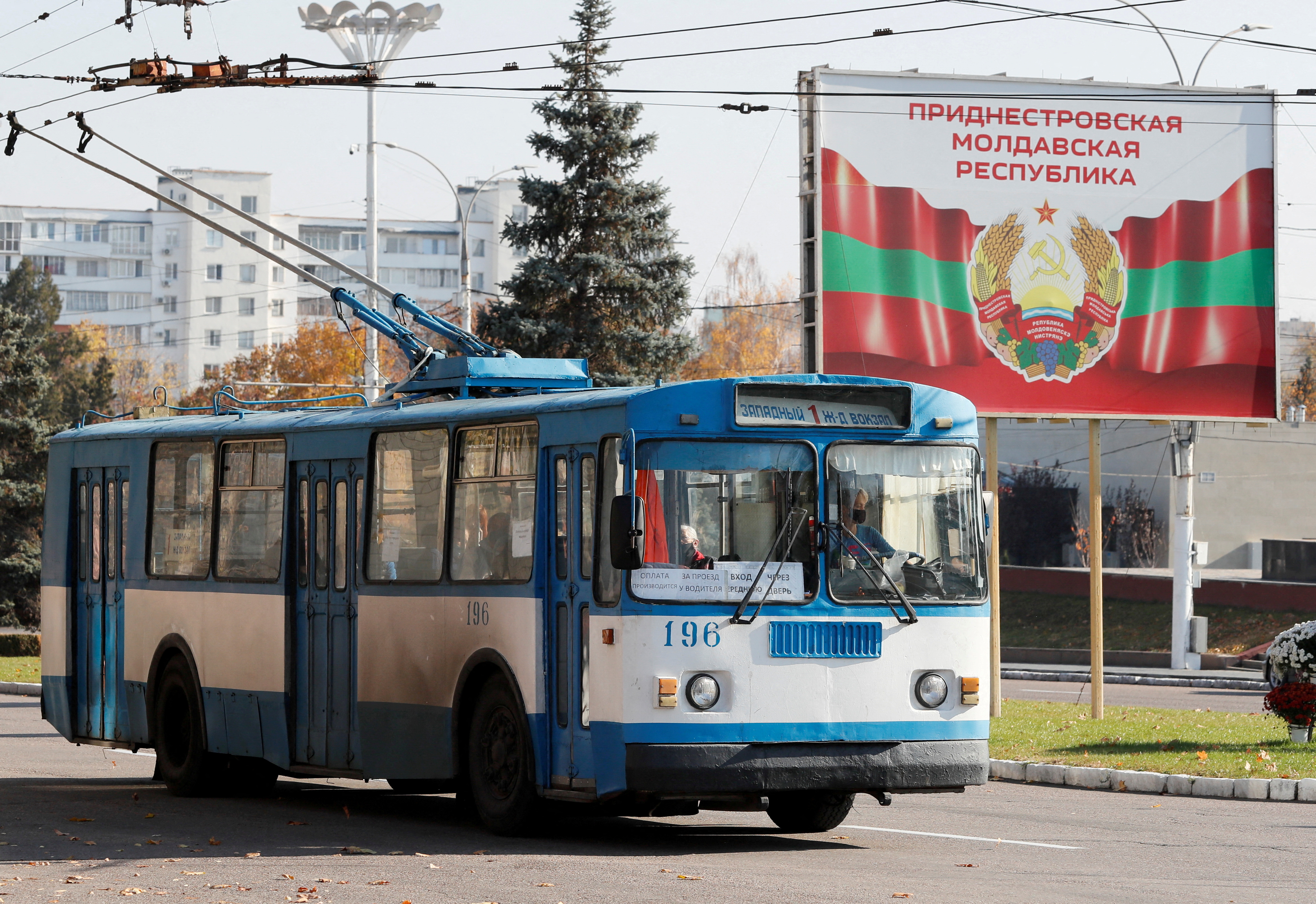 Un viejo trolebús circula cerca de un cartel con el escudo oficial en Tiraspol, en la autoproclamada Transnistria separatista de Moldavia, el 3 de noviembre de 2021 (REUTERS/Gleb Garanich)