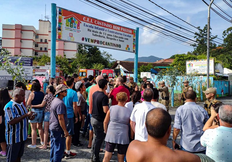 Gente de pie fuera de una guardería después de que un hombre de 25 años de edad atacó a niños en Blumenau, en el estado sureño brasileño de Santa Catarina, Brasil, el 5 de abril de 2023 (REUTERS/Wellington Civiero)